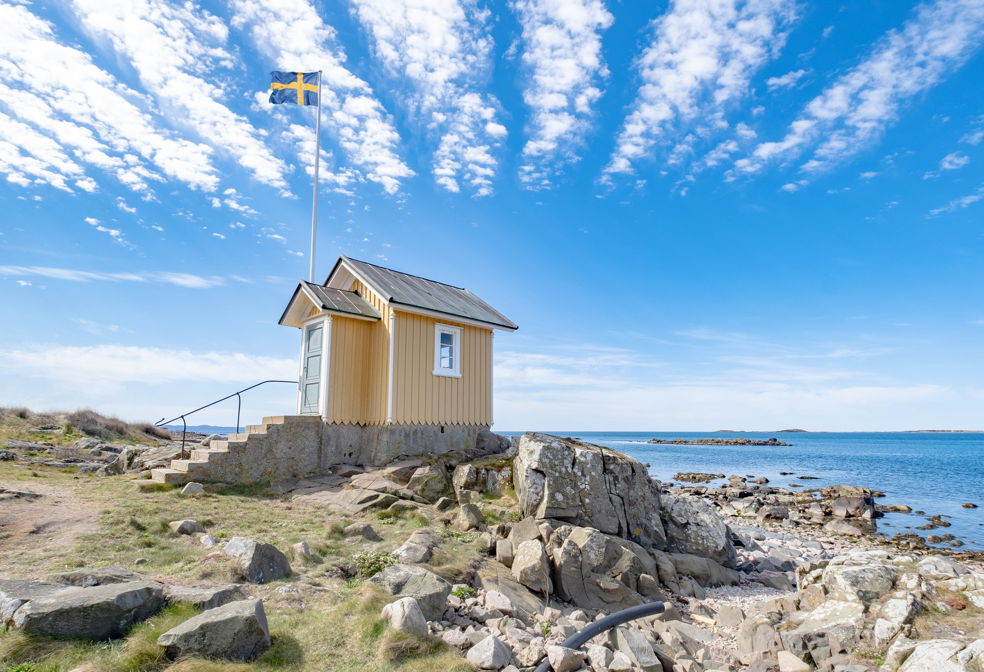 A small, yellow, wooden house along the beach in the seaside village of Torekov in Sweden. ; Shutterstock ID 1708695370; Purpose: Landing page; Brand (KAYAK, Momondo, Any): momondo