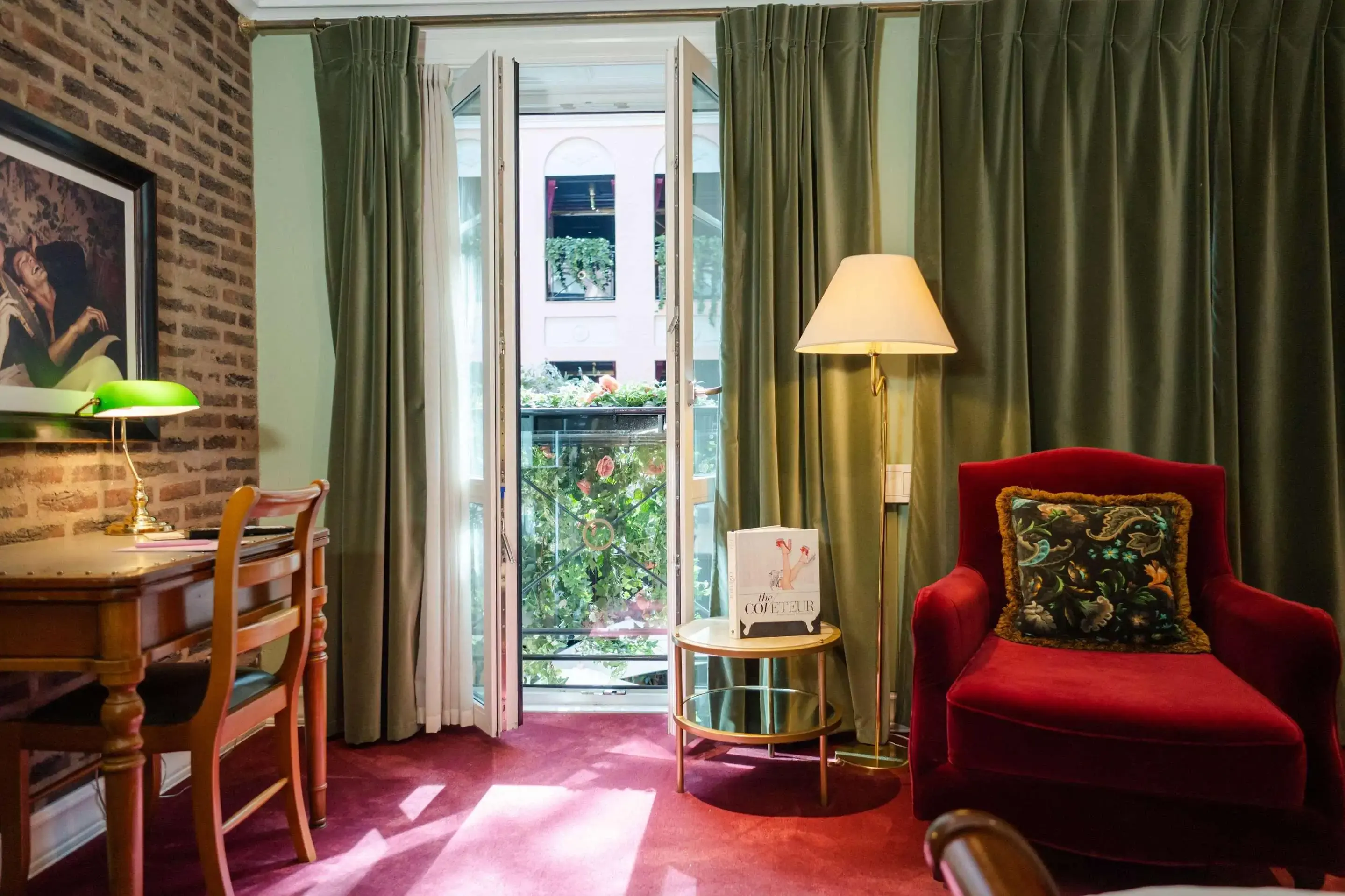 a hotel room with velvet green curtains and a red velvet armchair