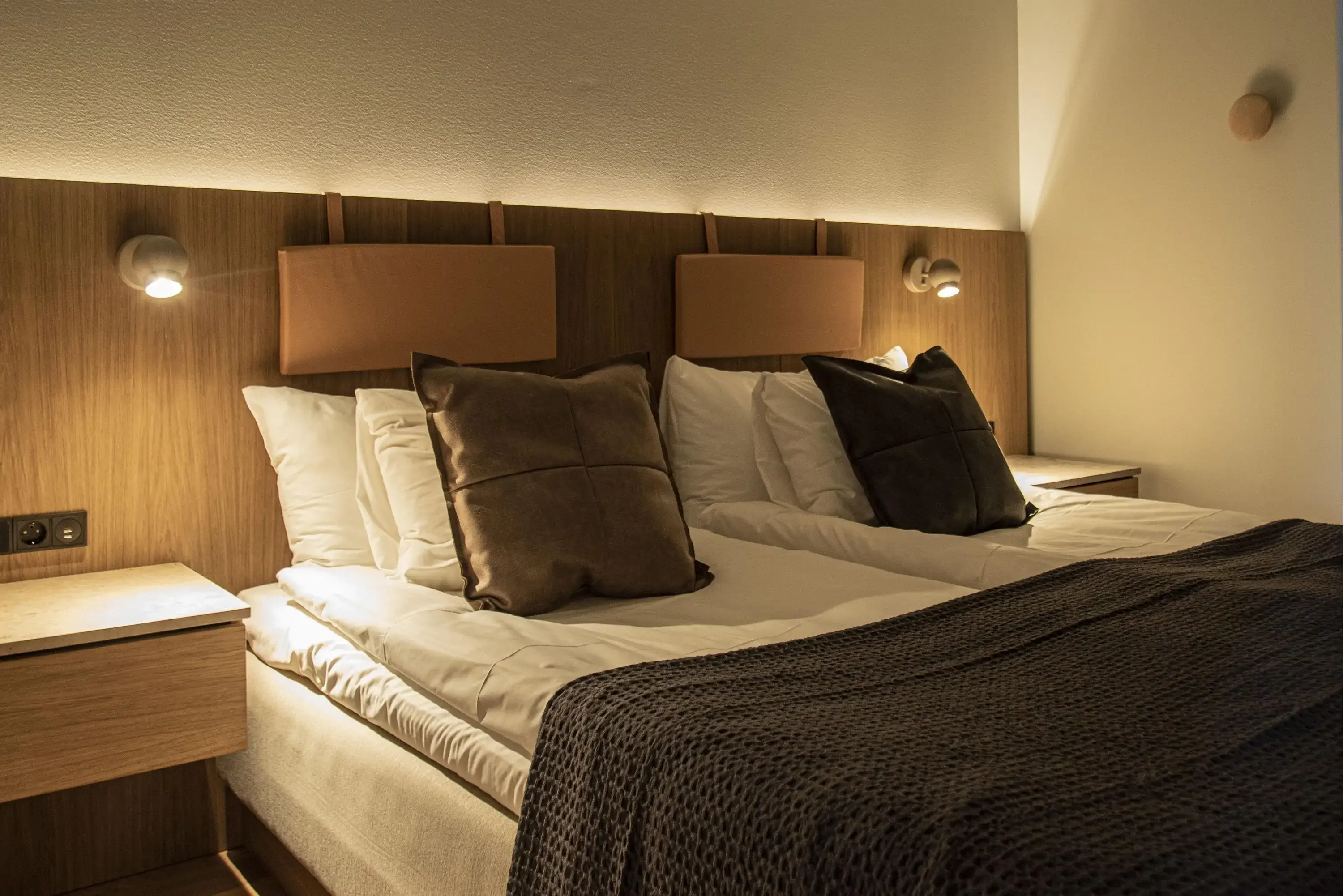 a closeup of a hotel bed with pillows and bedtables 