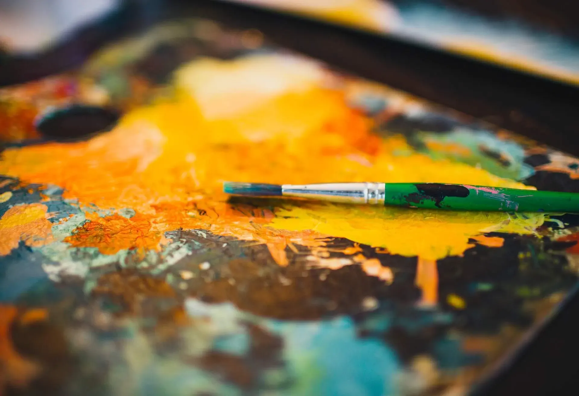 A paintbrush lies on colourful dried paint.