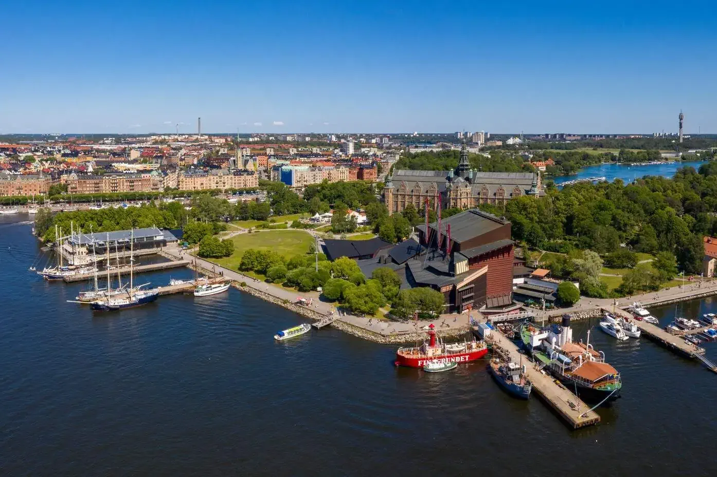Panoramic view of a harbour and a lush city by the river against the clear blue sky.