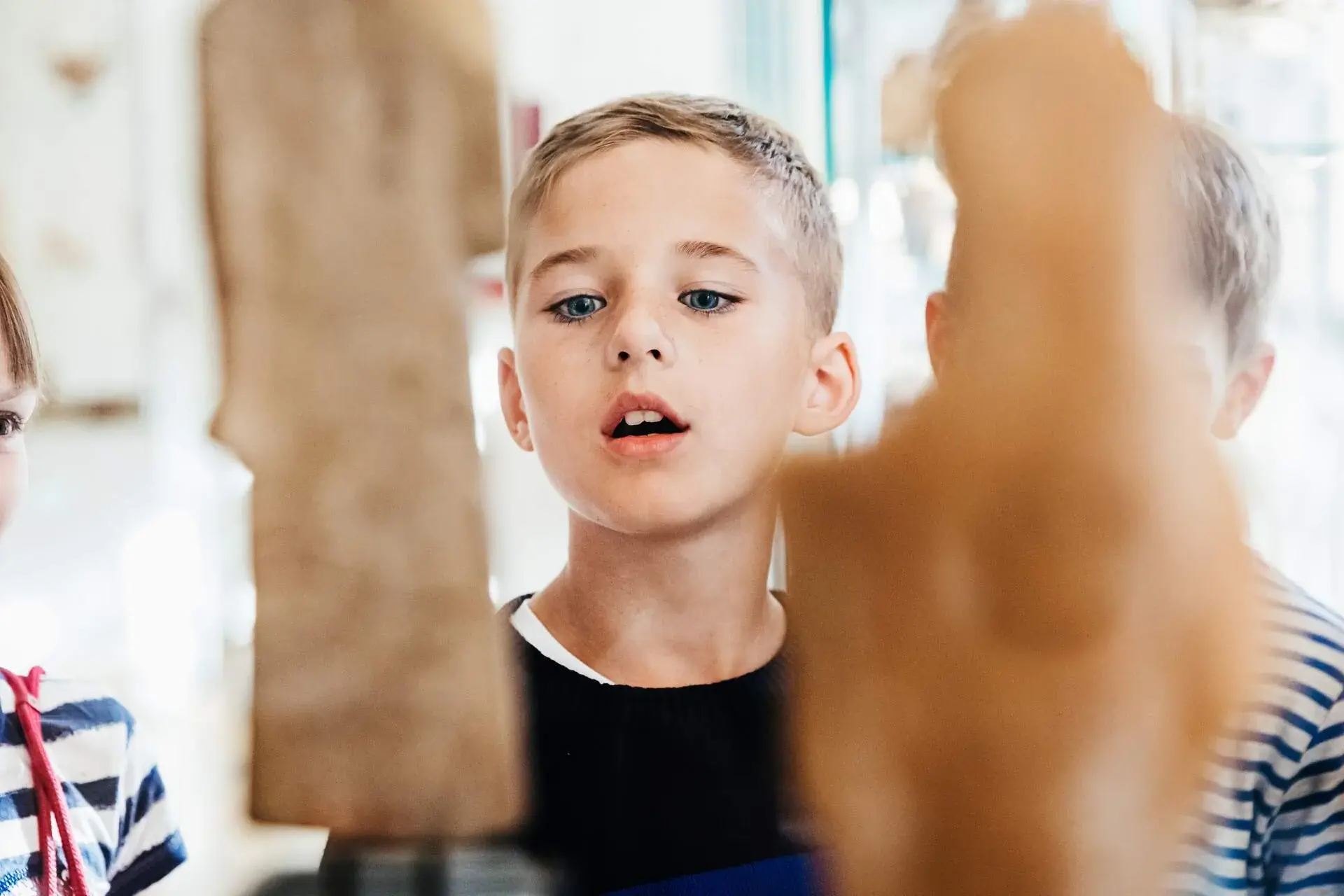 A curious young boy gazes in fascination at a collection of ancient artefacts on display, his eyes wide with wonder as he takes in the rich history and stories behind each relic.
