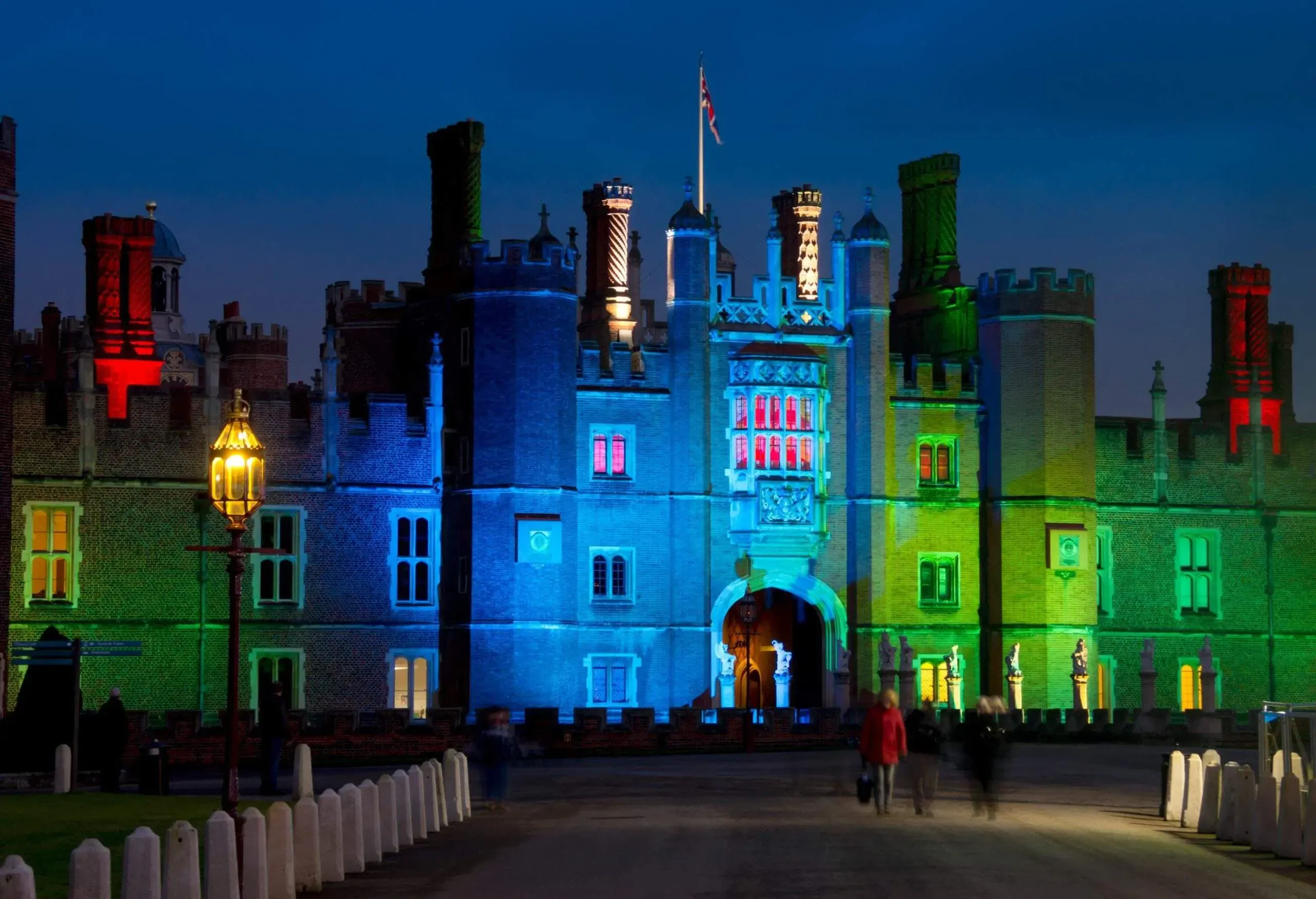 The facade of a royal palace is illuminated with different colours at night.
