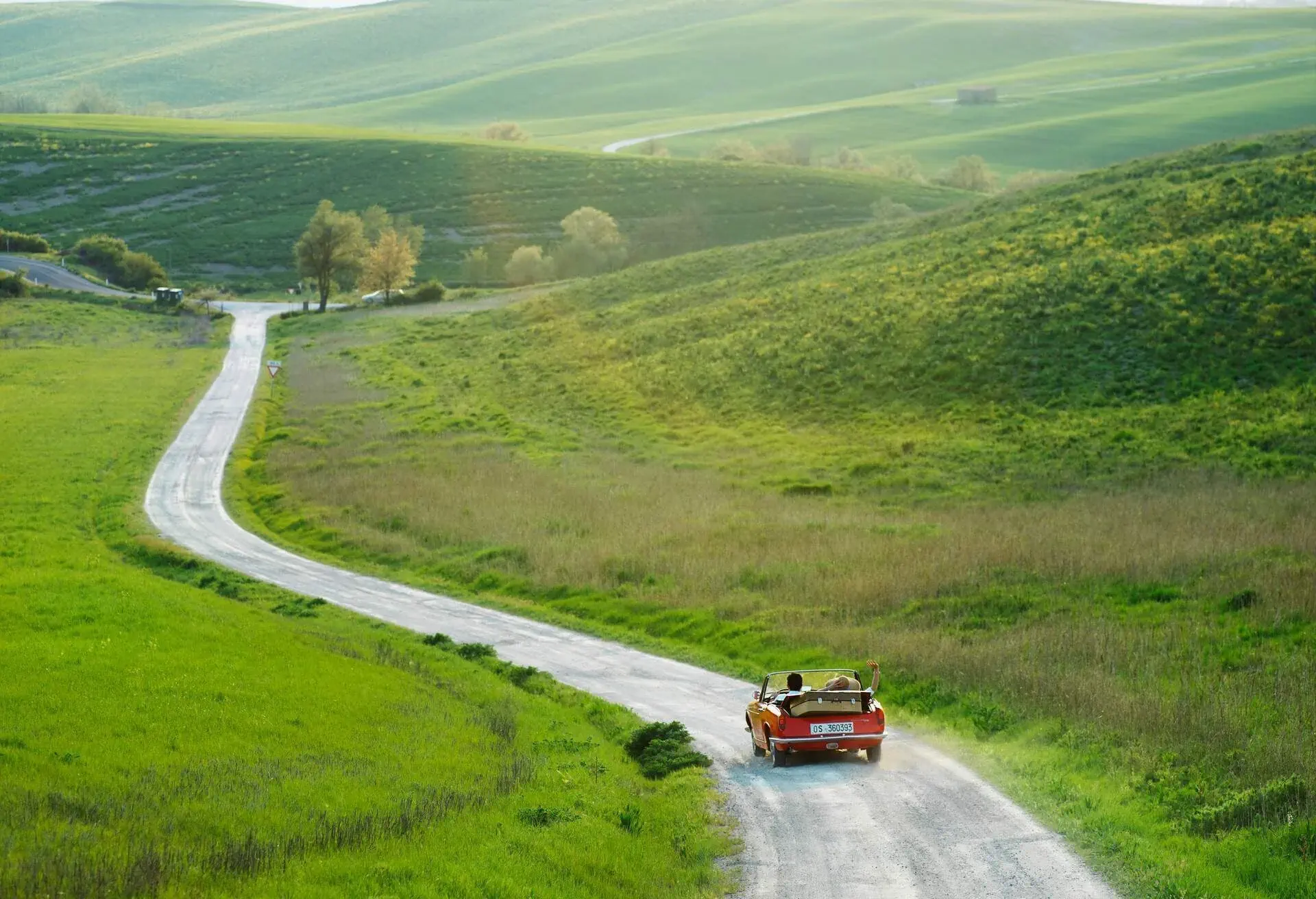 A red car driving in the Italian countryside