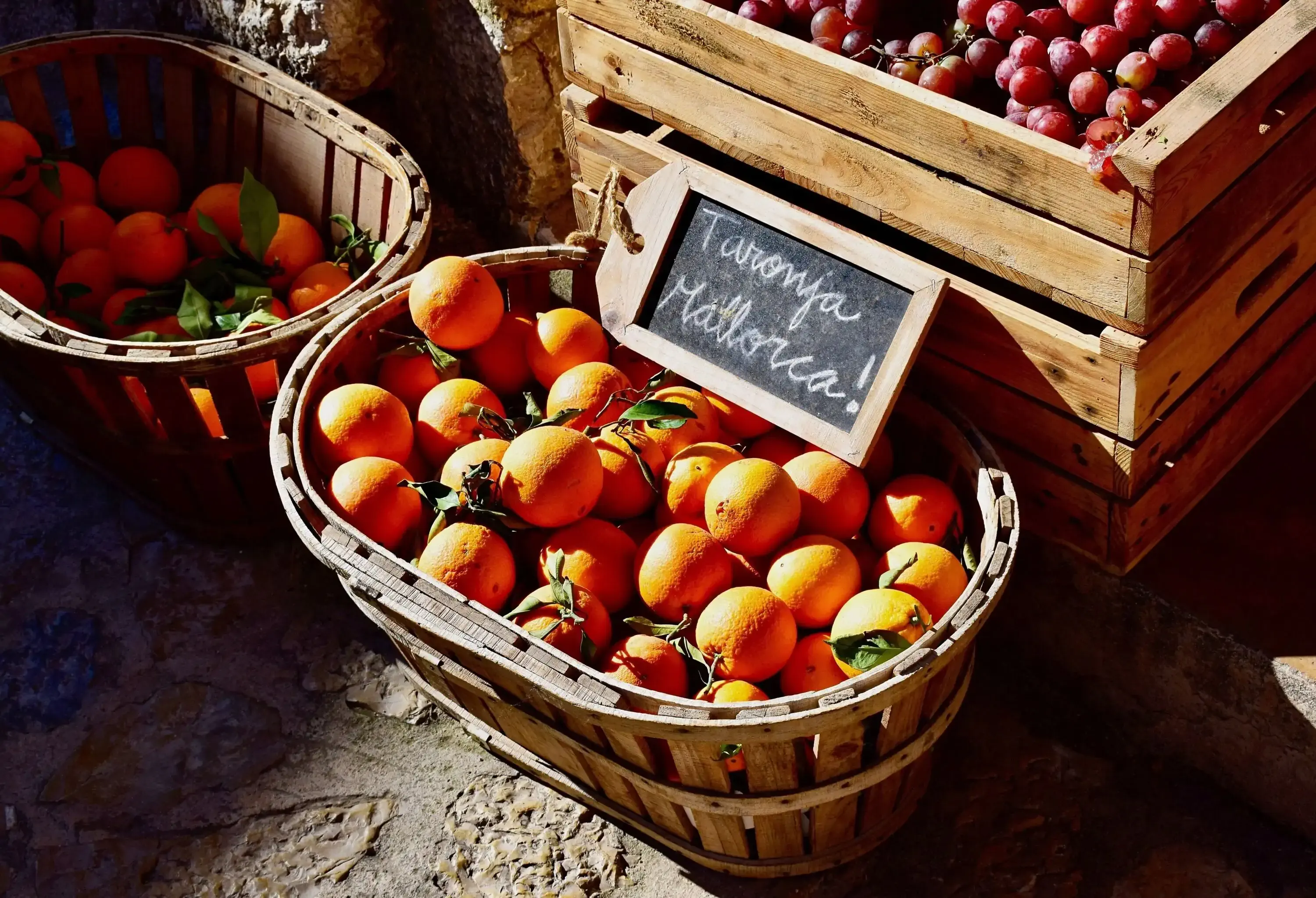 Orange fruits in the wooden baskets with a handwritten signboard.