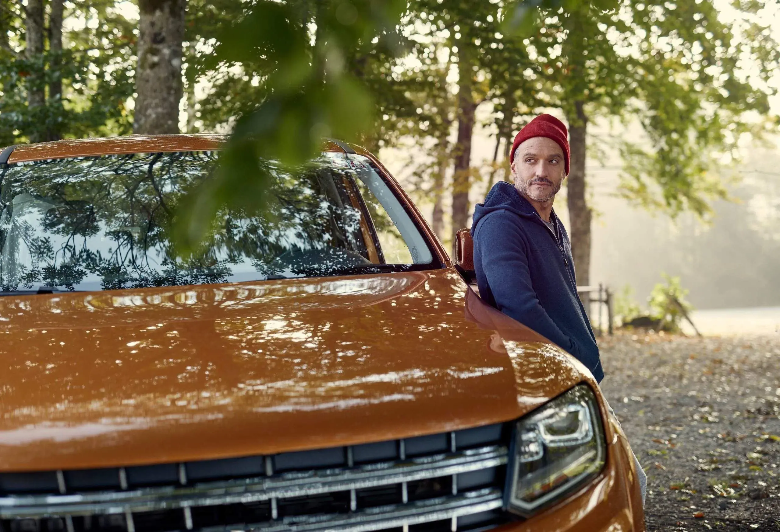 A man leaning on a car in the woods
