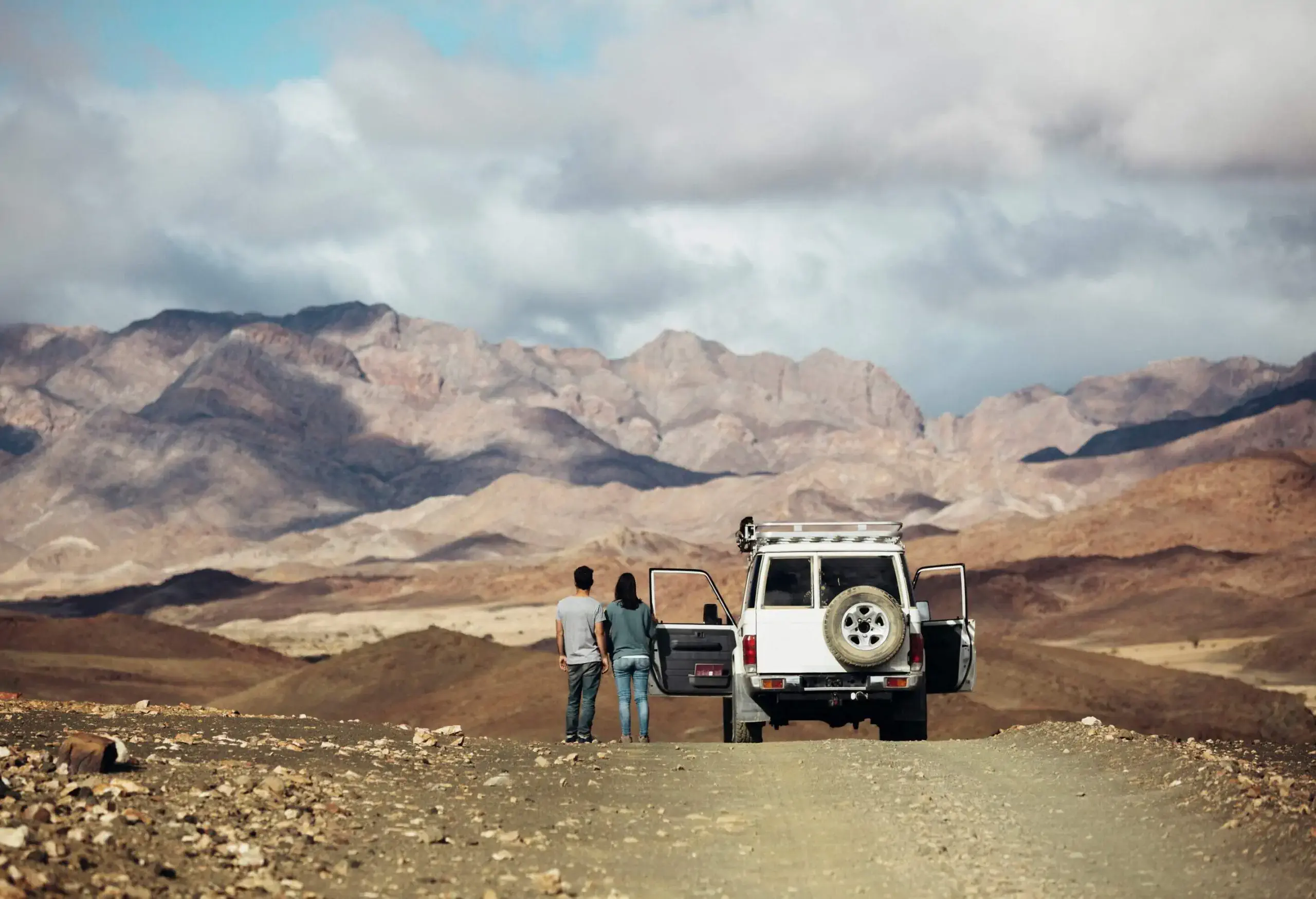A couple standing next to a 4WD in a desert