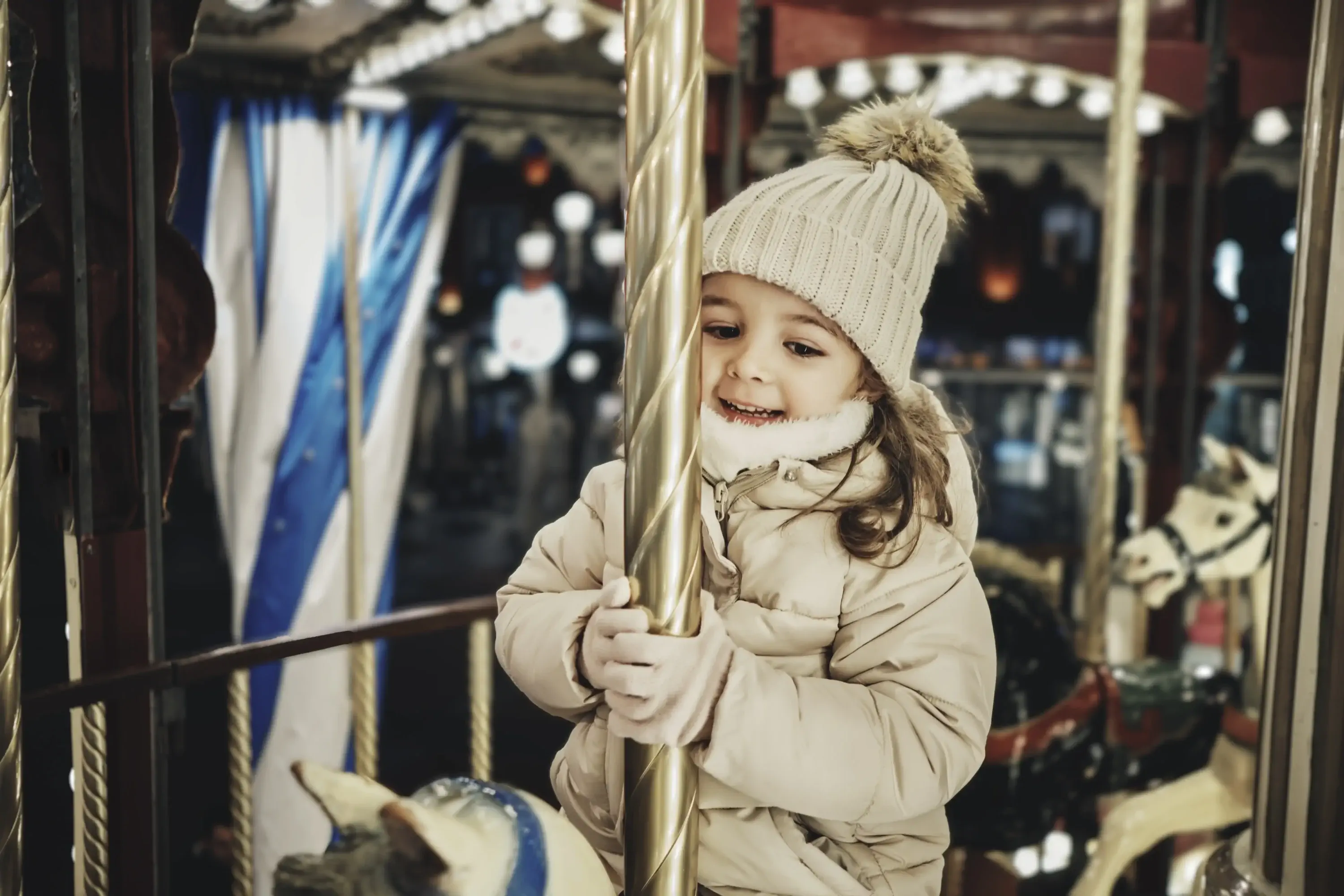 Smiling girl enjoying carousel horse ride at Christmas market