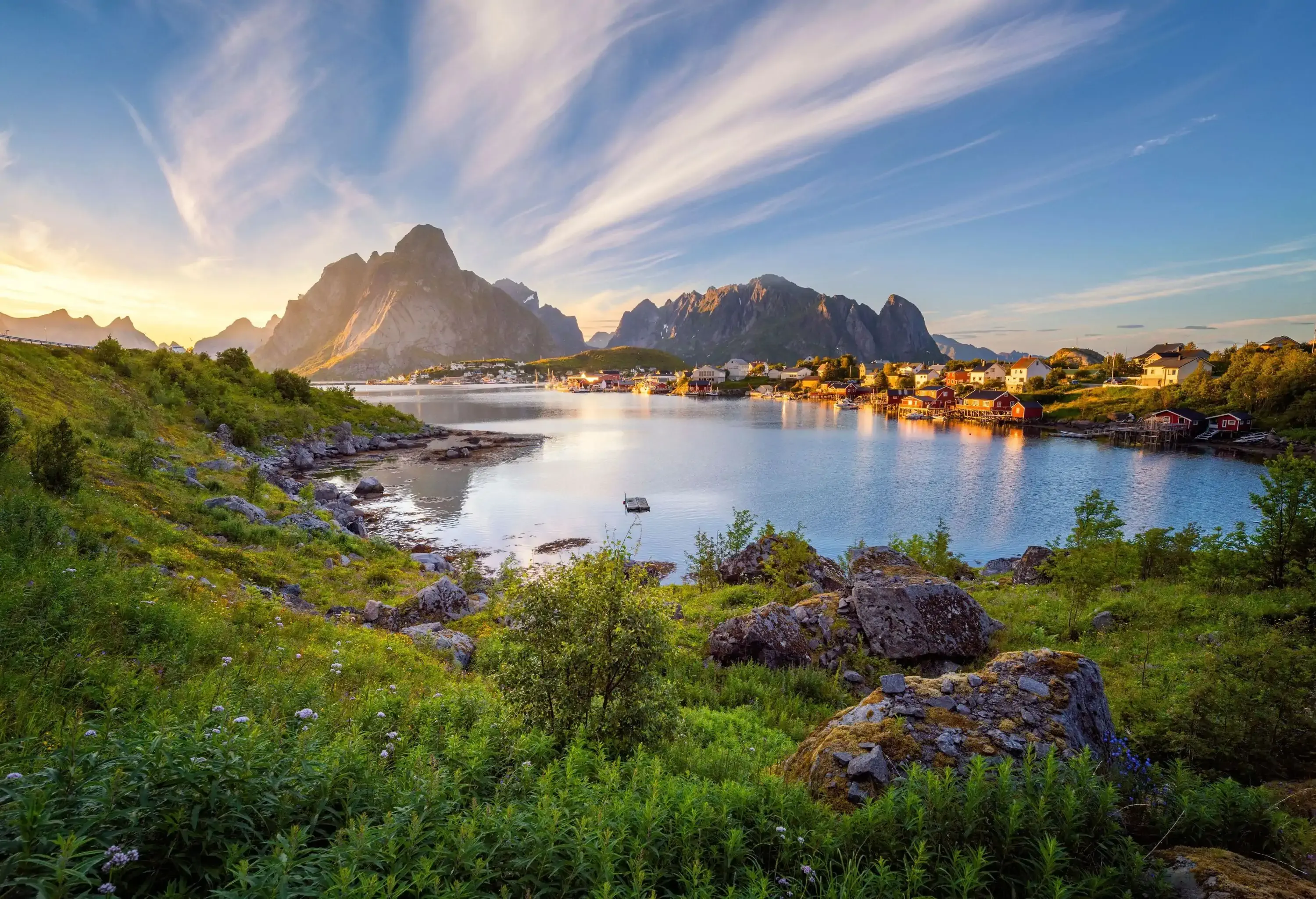 A small waterfront village with craggy mountains in the background.