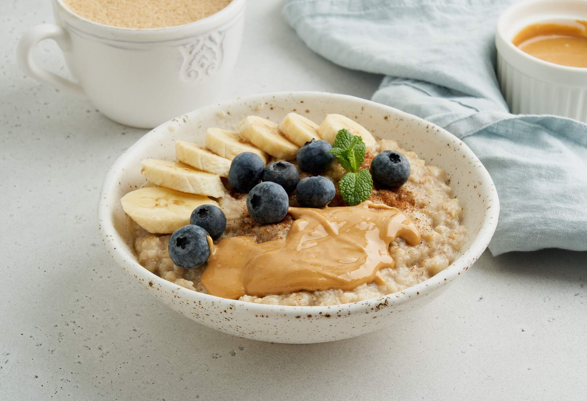 Oatmeal porridge. Traditional bunting breakfast served in ceramic bowl on gray background. Vegetarian and nutritious vitamin morning eating. Classic hot homemade dietary meal