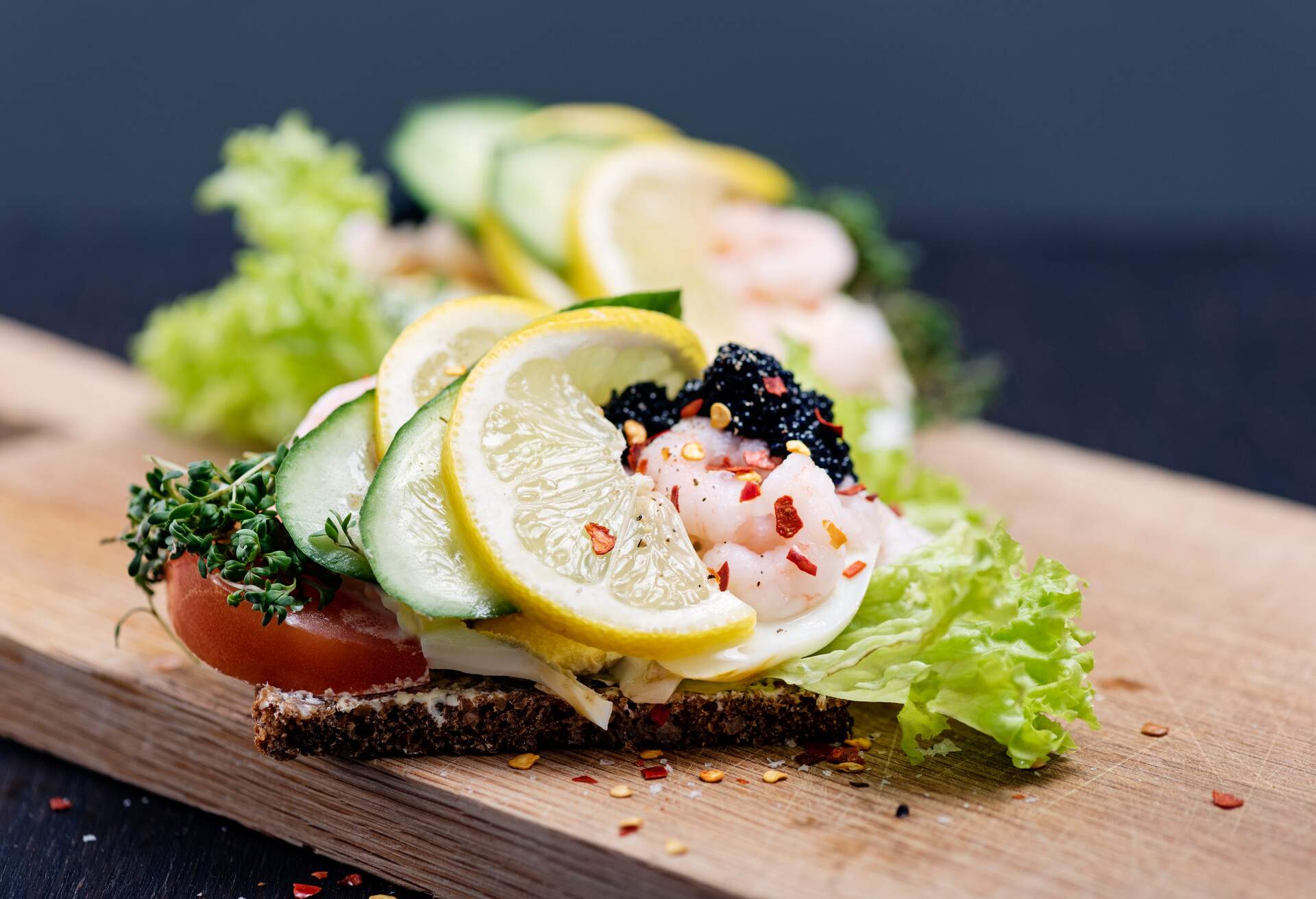 Smørrebrød is a traditional open faced sandwich made with dark rye bread with various cold toppings. Toppings range from egg, smoked fish to cold meats with various pickles and herbs added. Traditionally eaten at lunchtime or occasionally at the end of a party. Egg with prawn and caviar, colour, horizontal with some copy space.