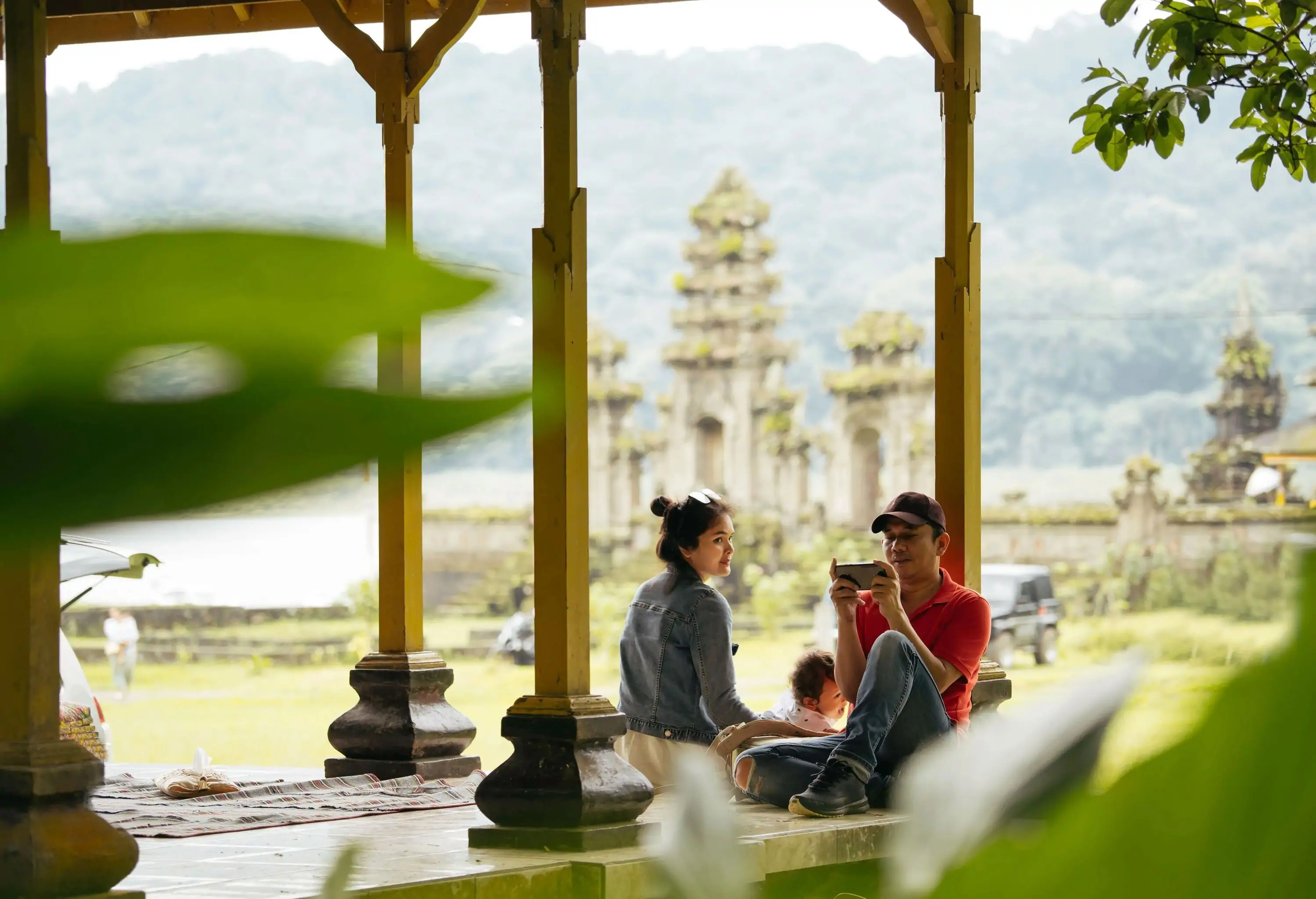 Asia, Indonesia, Bali, asian family sitting inside pavillion enjoy the travel, in front of Tamblingan water temple, while sightseeing.