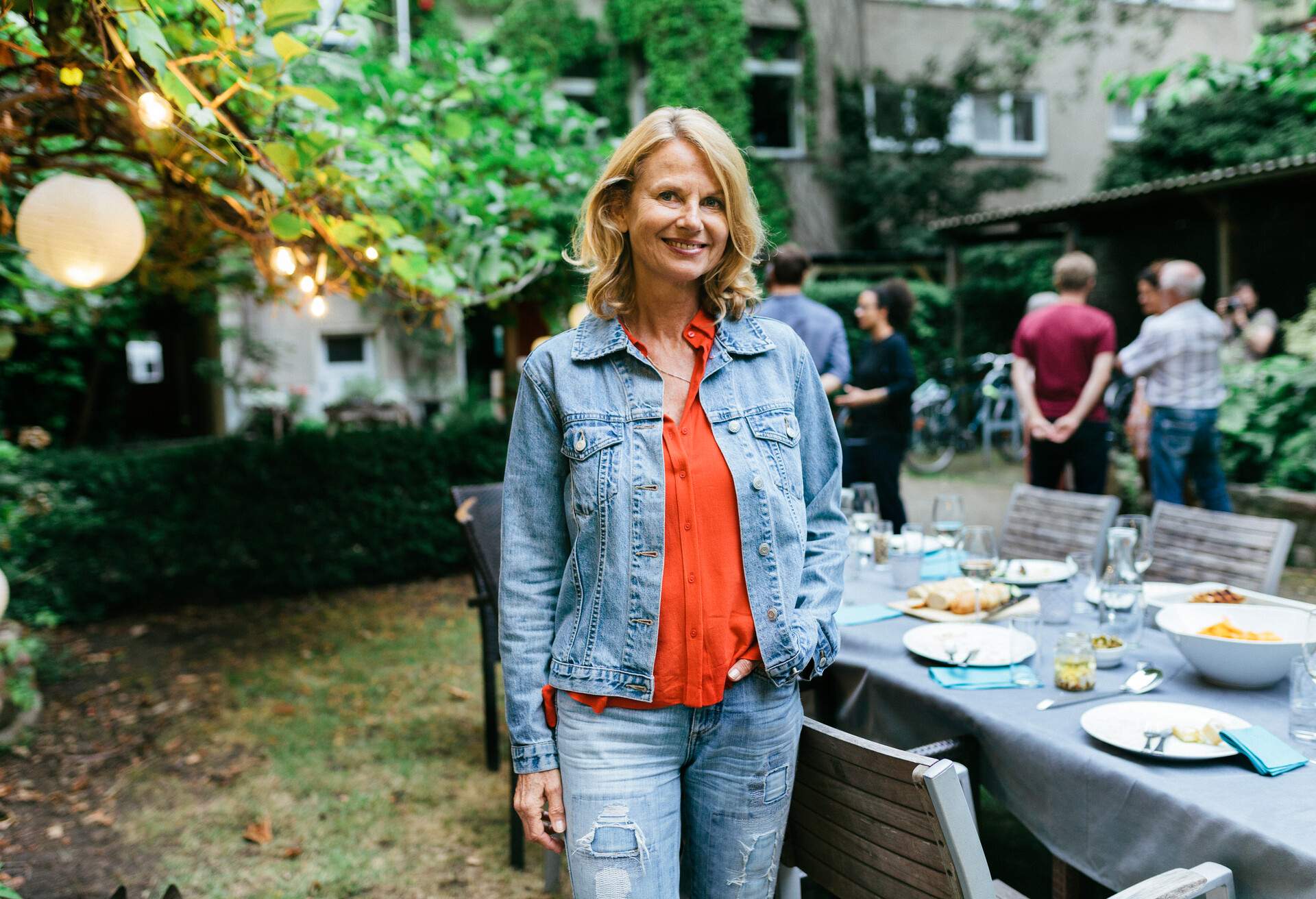 A portrait of a woman smiling after enjoying a barbecue meal with her family outdoors.