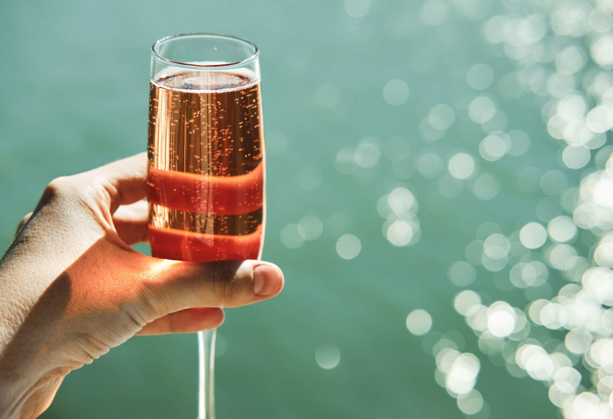 A glass of pink champagne in one hand.