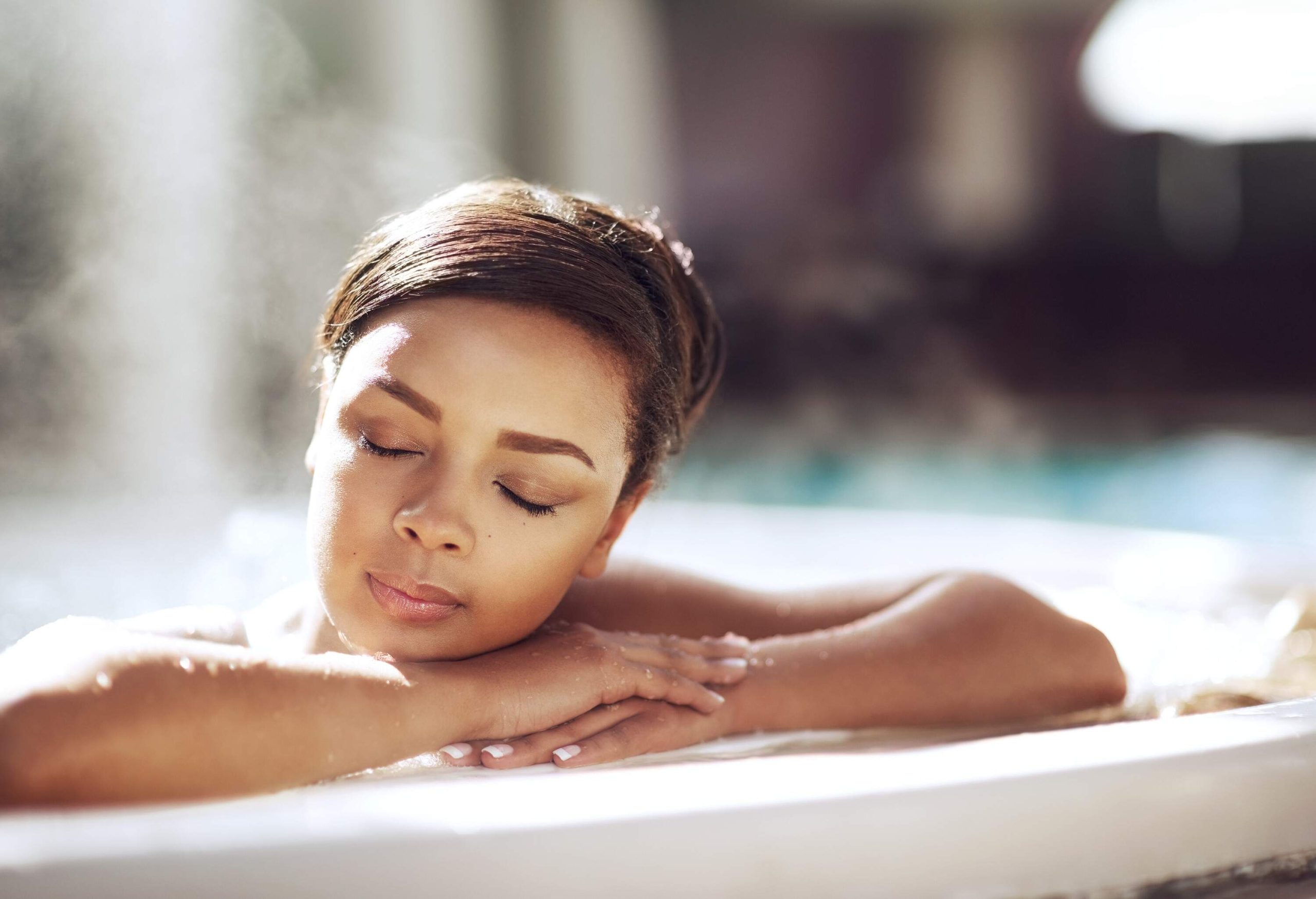 A woman relaxes in a hot tub with her eyes closed.