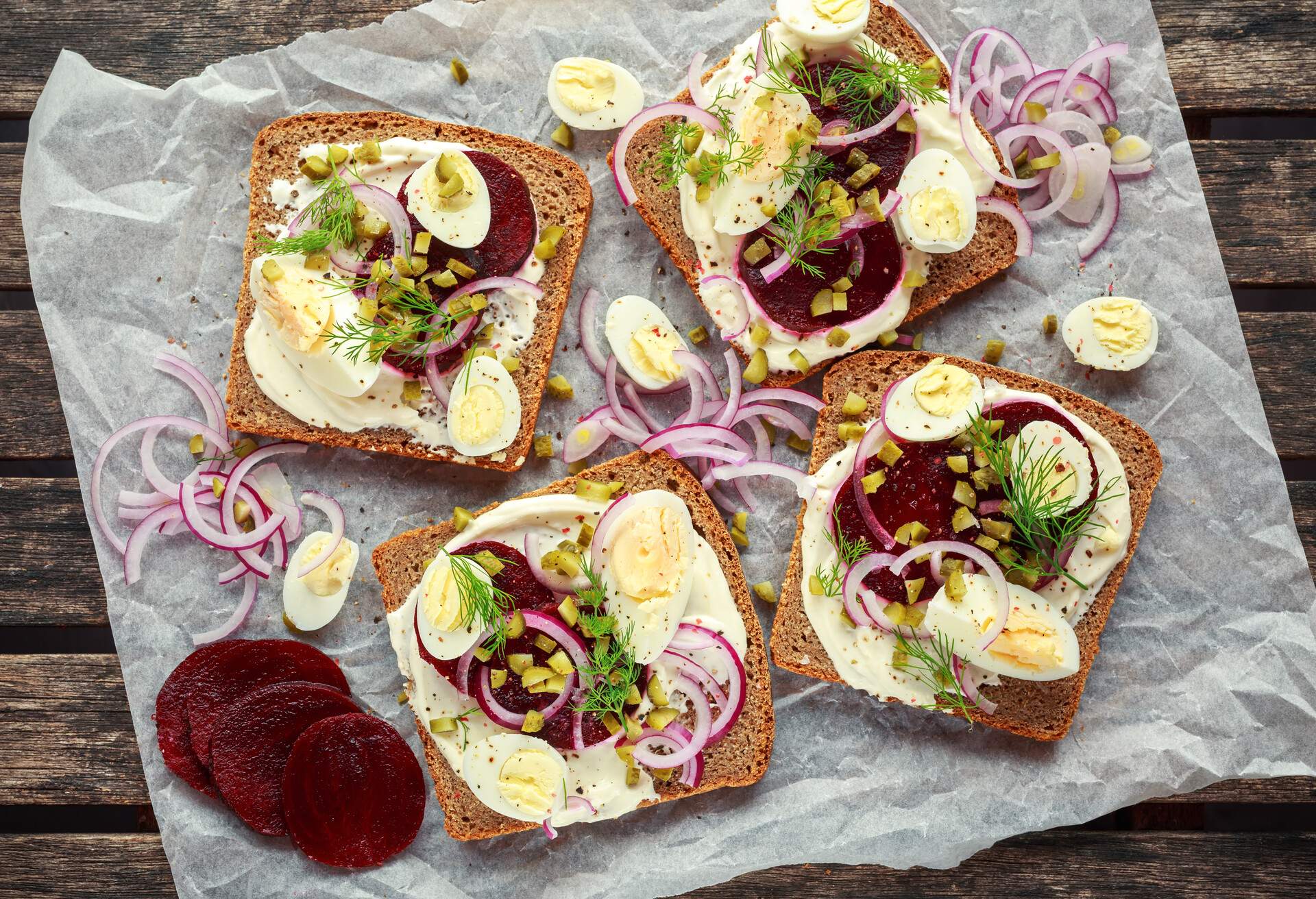 Danish open-face rye sandwich with quail eggs, beetroot, pickled onions and cucumbers drizzled with dill.