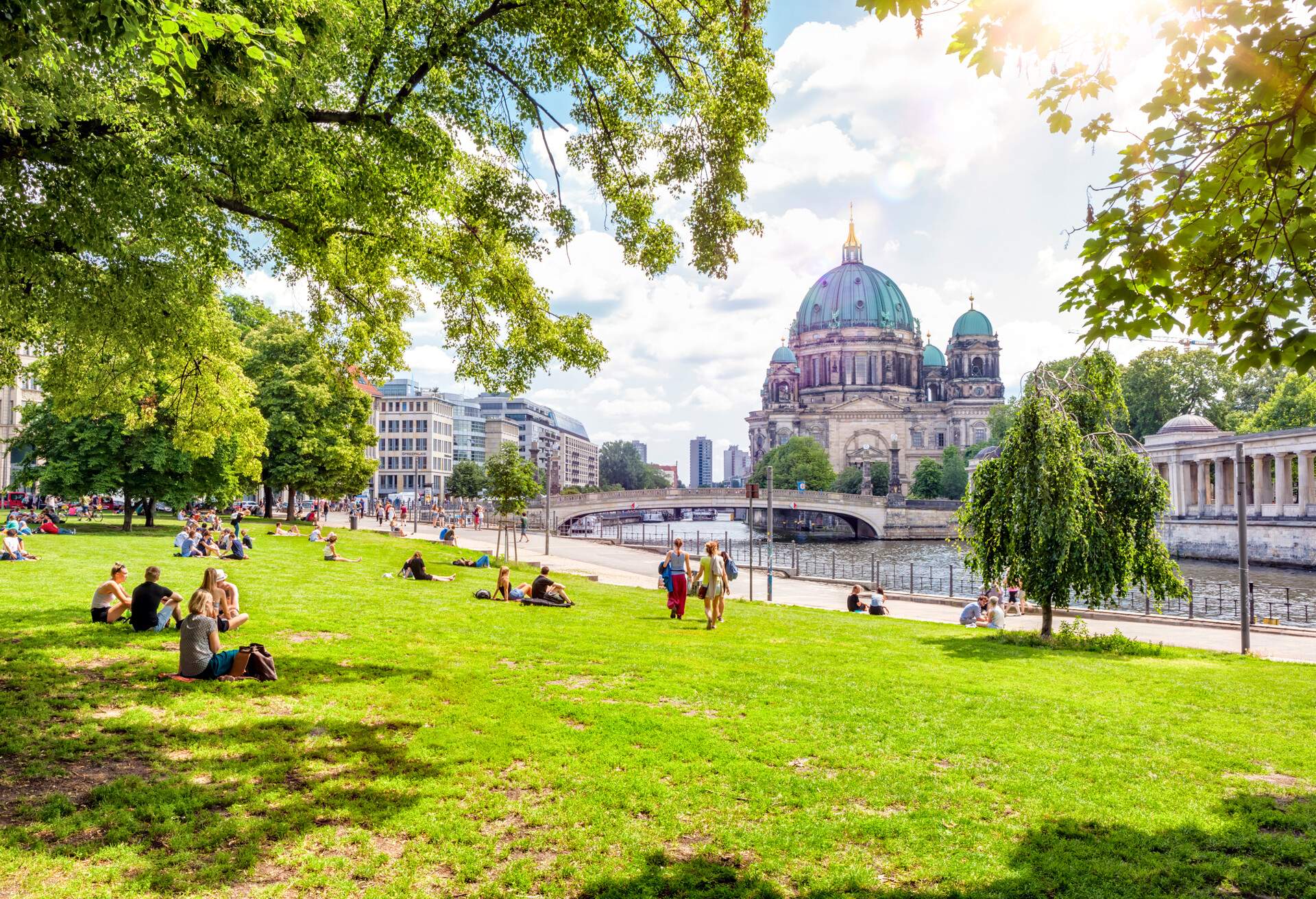 People enjoying a sunny day at a park by the river overlooking the Berlin Cathedral, Berlin, Germany
