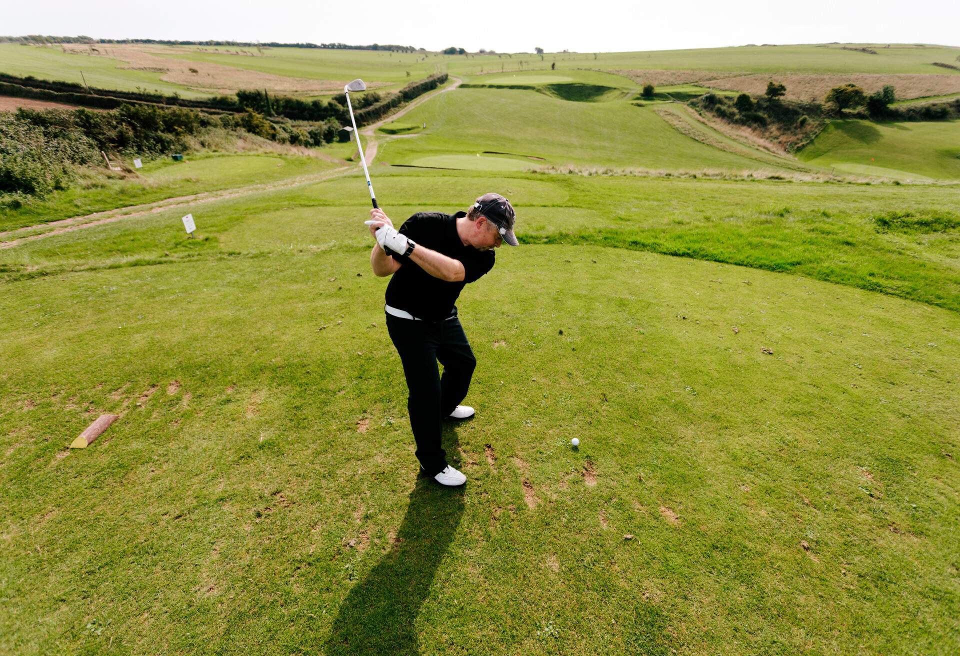 A male golfer takes a drive from the 7th tee on a beautiful coastal links golf course in Devon. Axe Cliff Golf Club, Axmouth, Devon