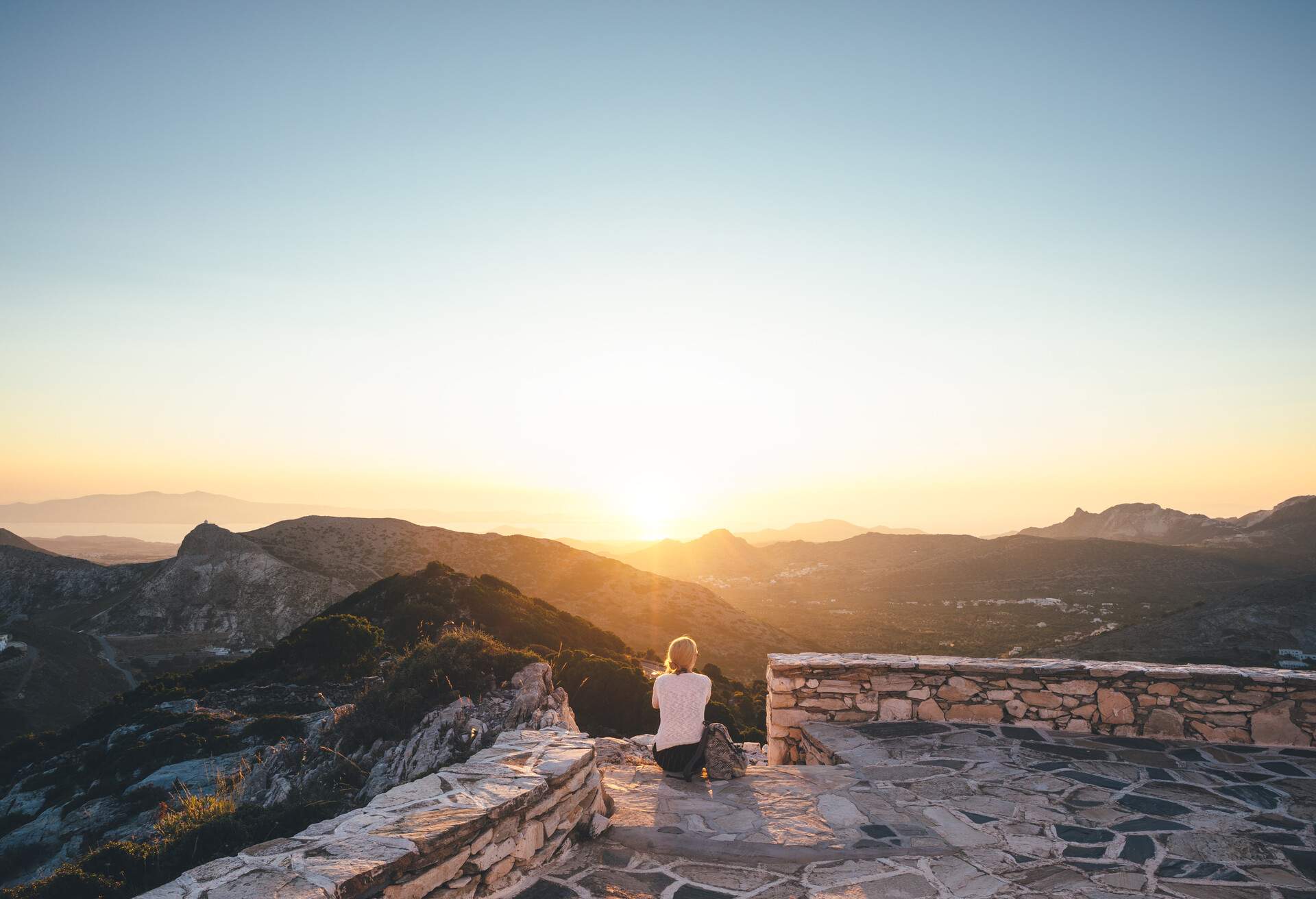 Young woman enjoying the sunset from the church on top of the hill (Naxos, Greece)