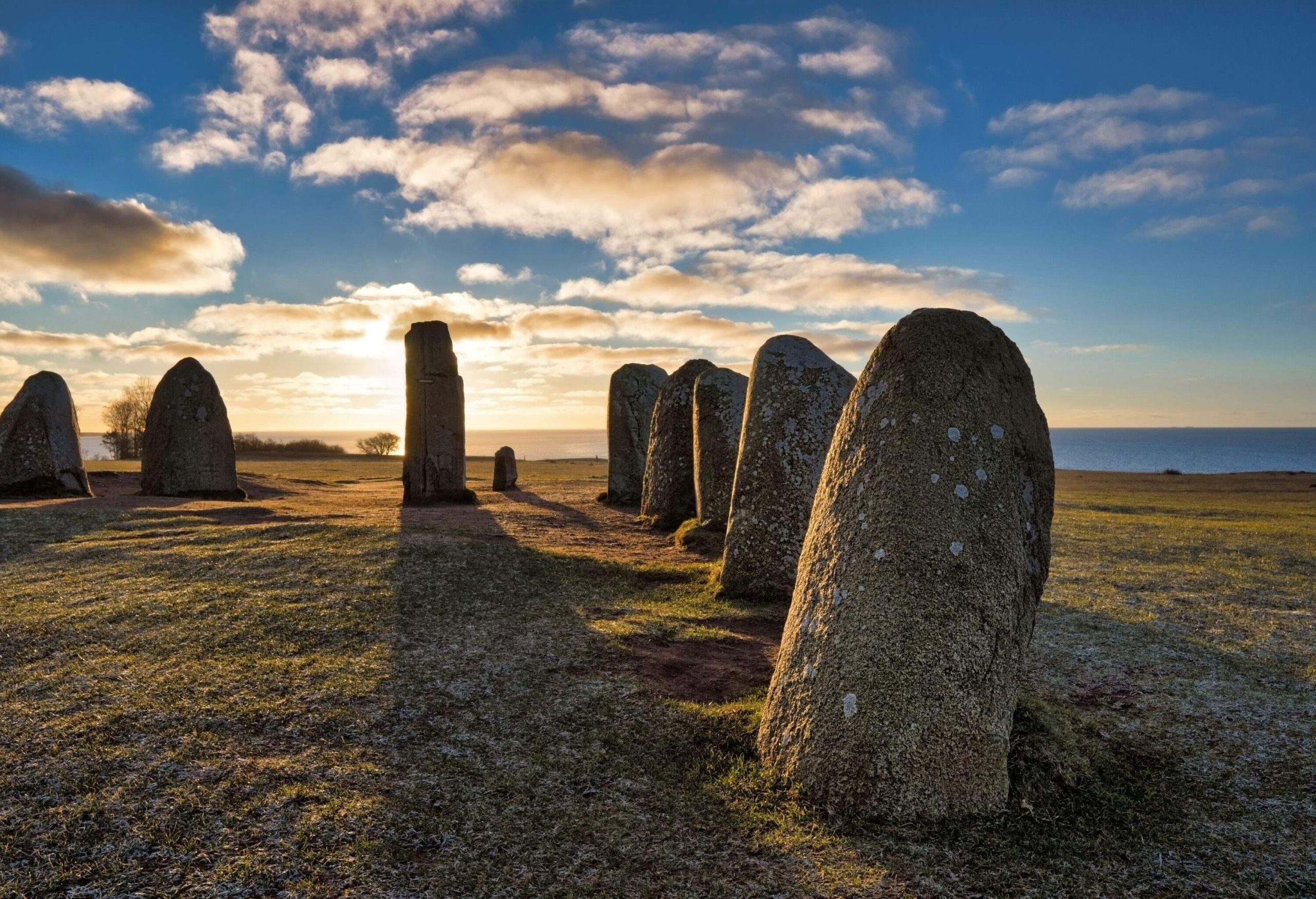 Ale's Stones megalithic monuments are large stone boulders on grassland with a sea view.