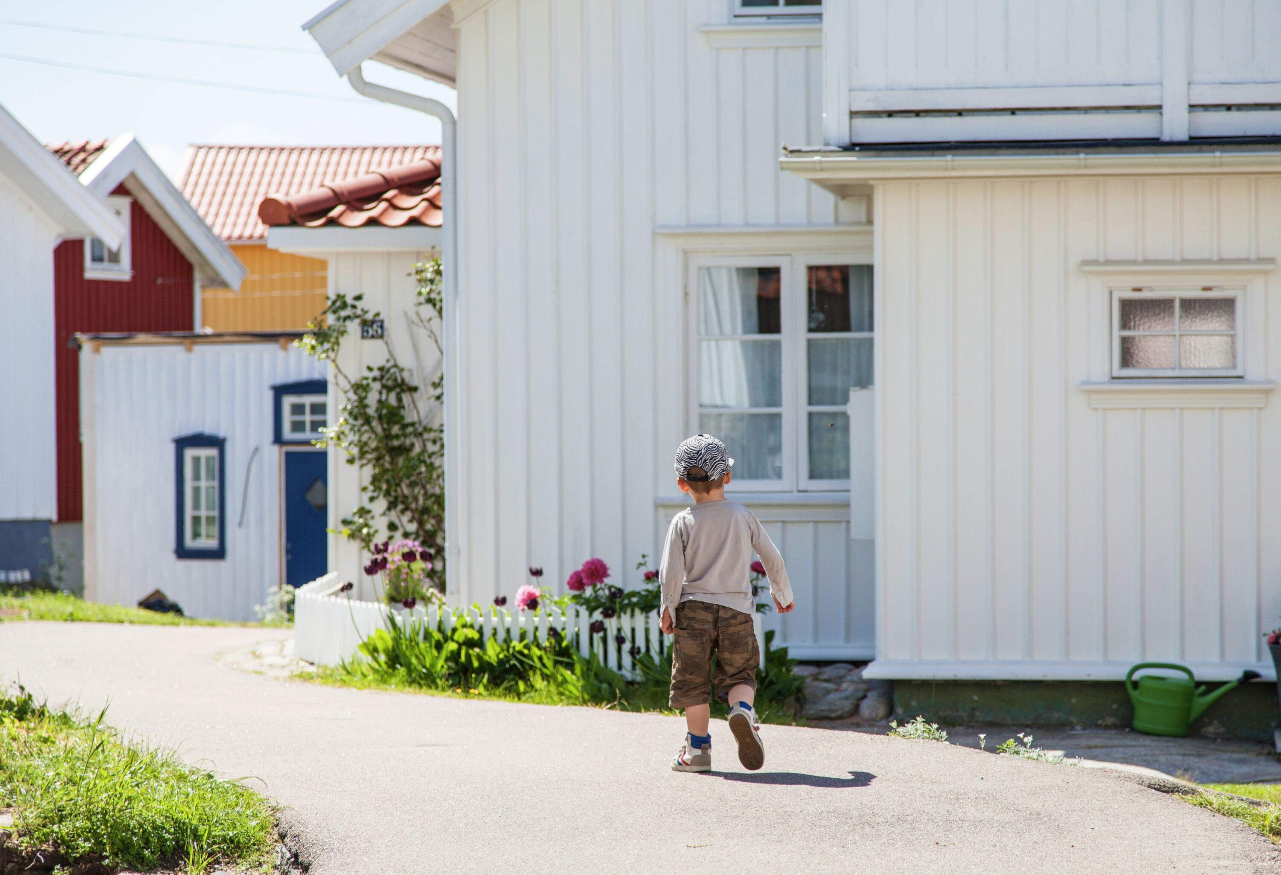 A kid walks on a path in a neighbourhood with white homes.