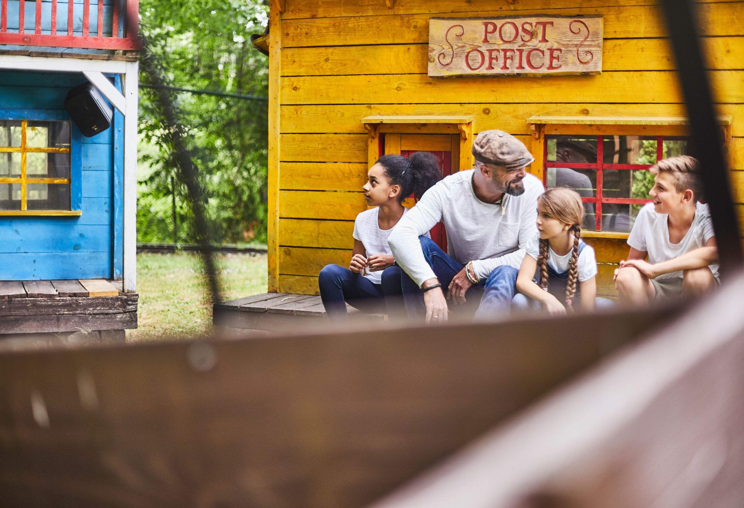 A cheerful family gathered together in front of a quaint Western-style mini house.