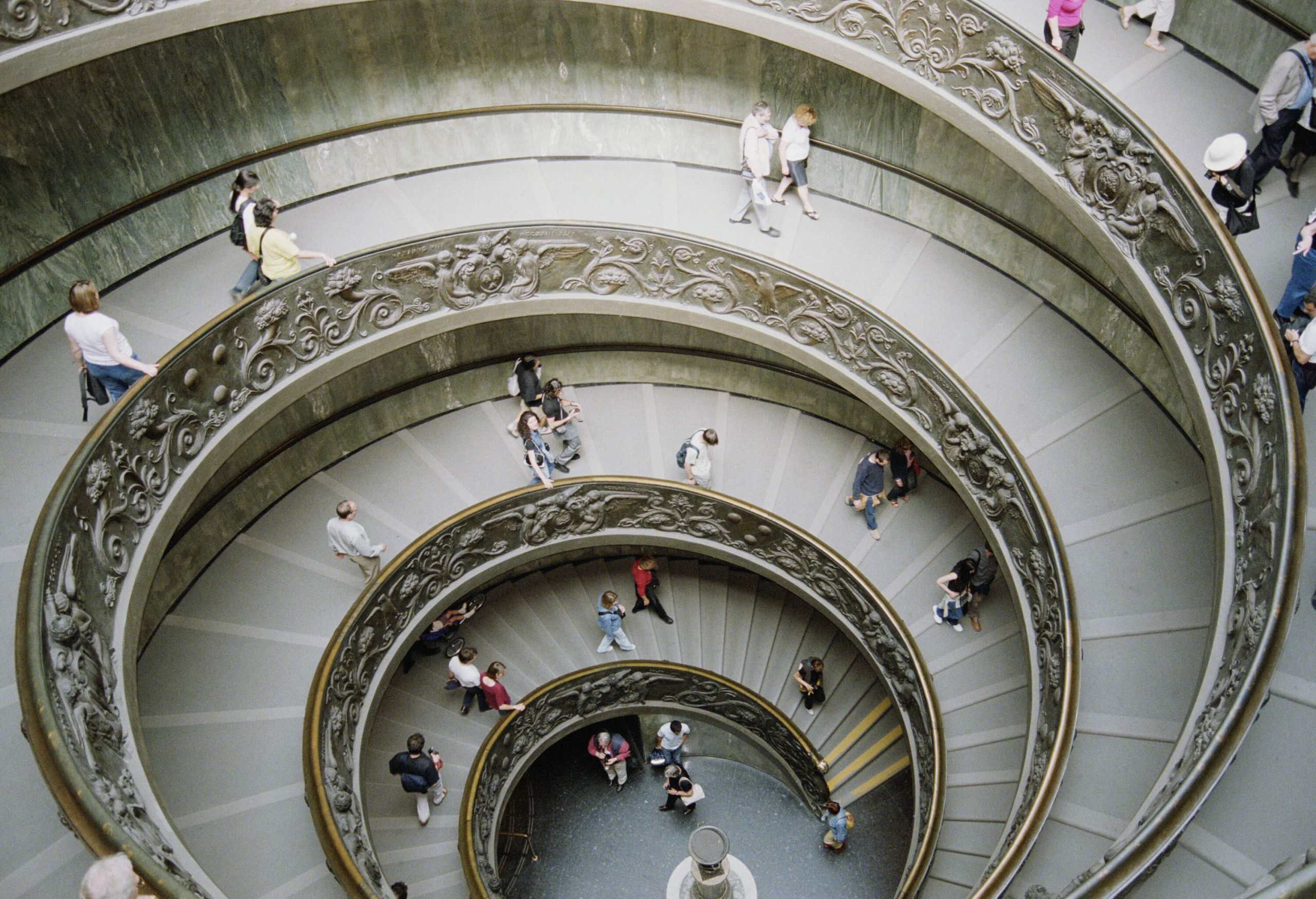 Visitors gracefully descend a captivating spiral staircase at the Vatican Museum.