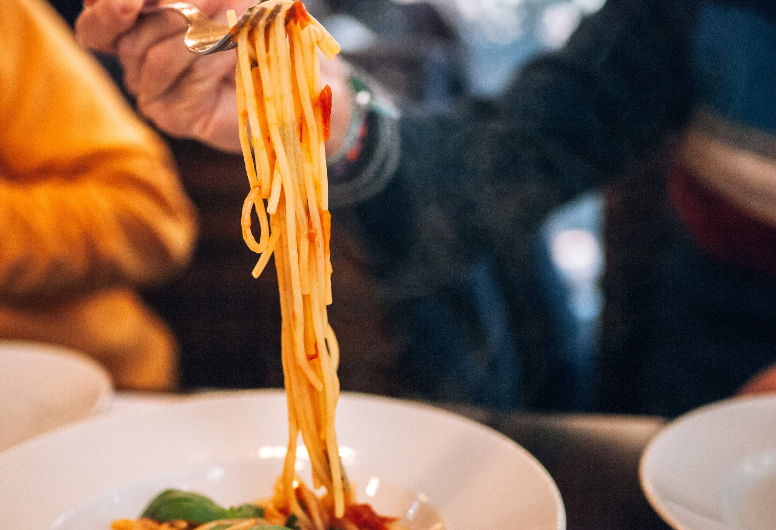 Strands of cooked spaghetti noodles dangling from a fork.