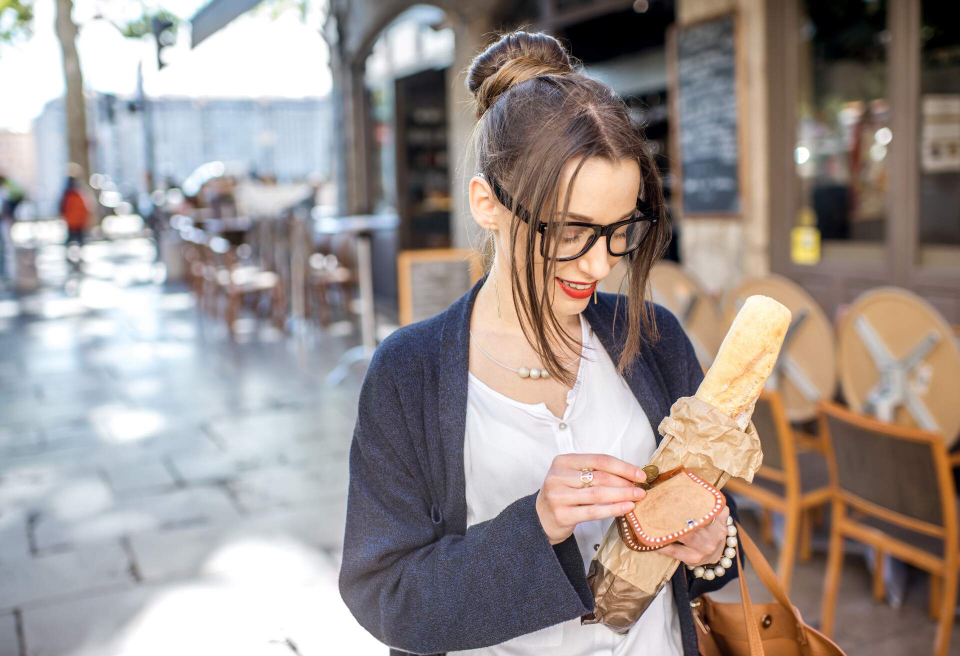 Young stylish woman buying a french baguette standing on the street in Lyon city