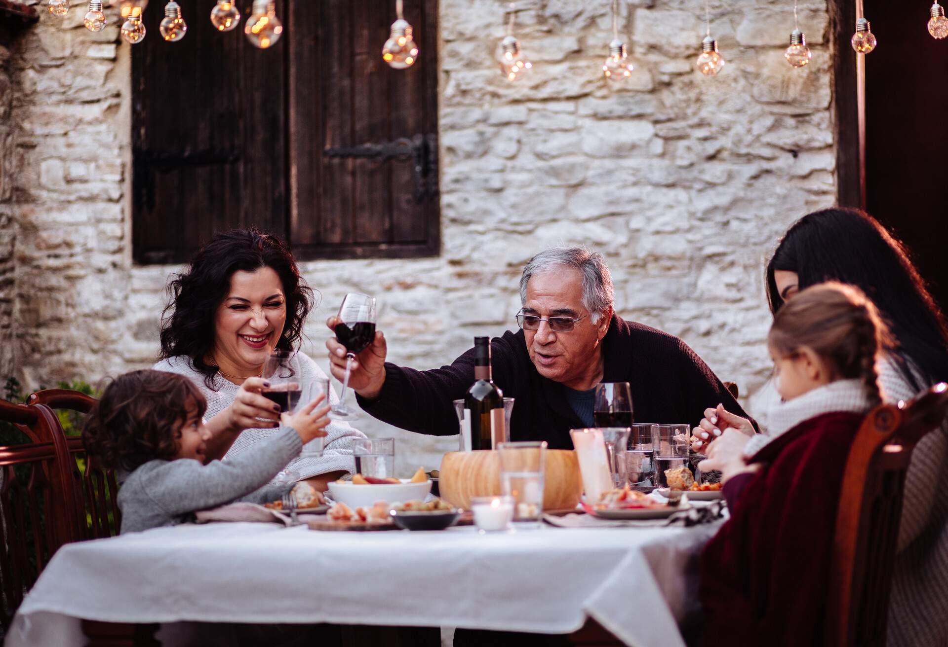 Grandparents toasting with grandson at lunch at rustic traditional house in mediterranean village