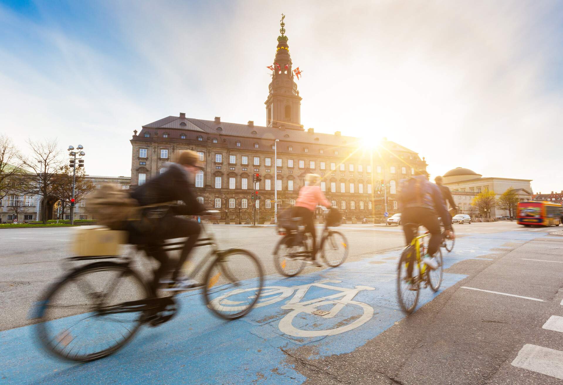 Blurred people going by bike in Copenhagen, with Christiansborg palace on background. Many persons prefer biking instead of taking car or bus to move around the city. Urban lifestyle concept.