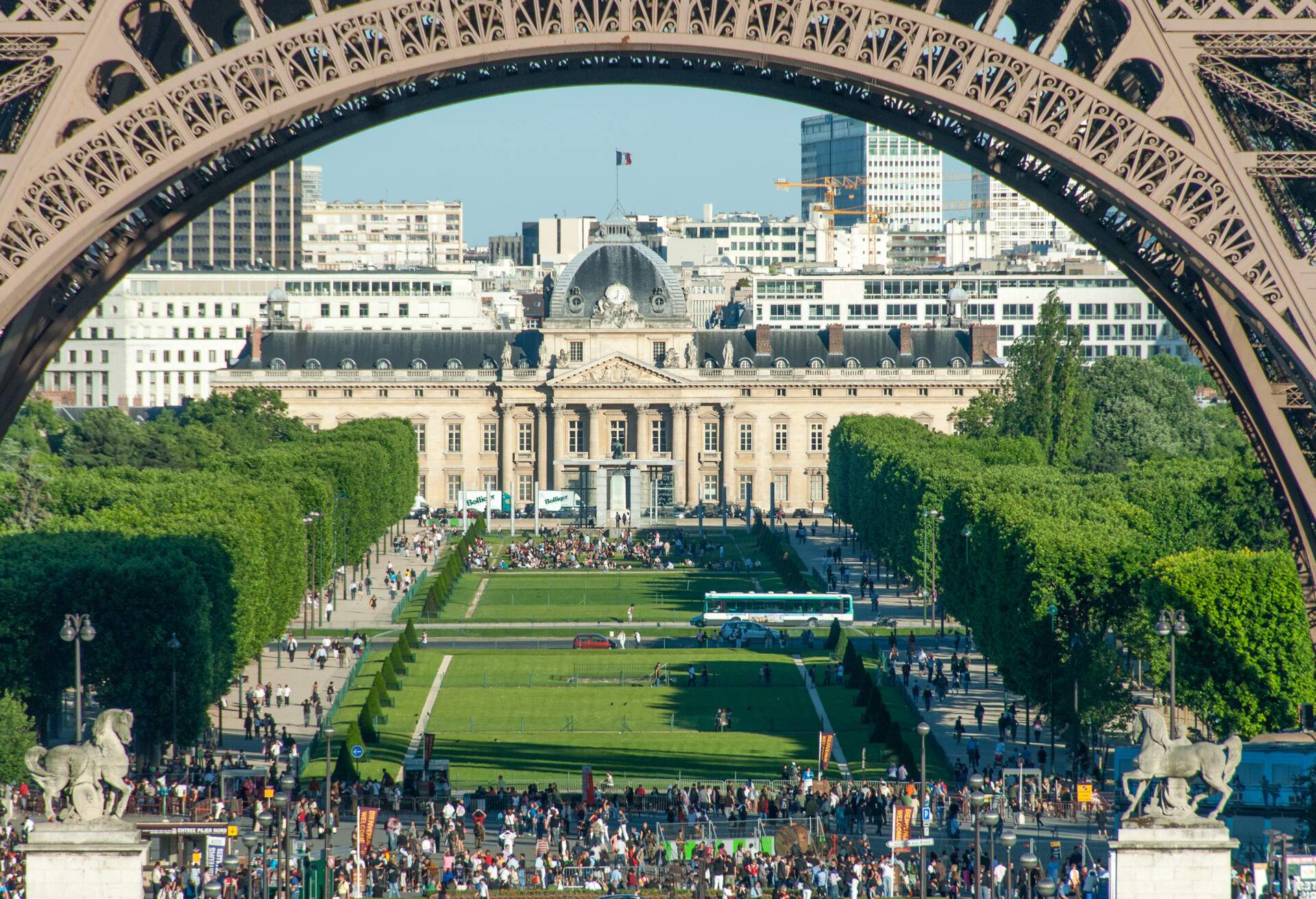 Crowds beneath the Eiffel Tower arches with a view of Champs de Mars