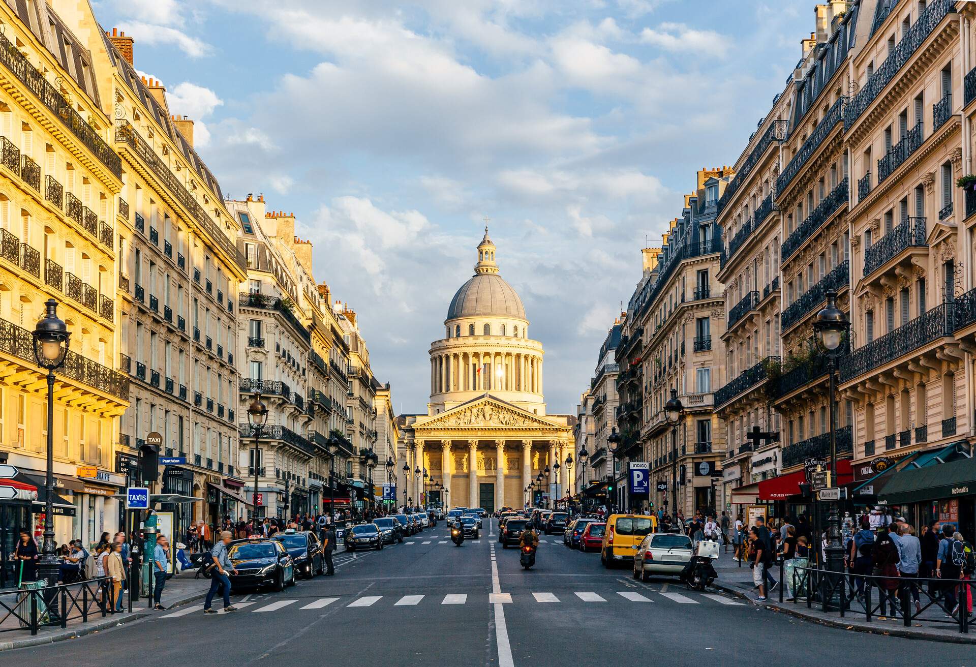 A bustling city street with the Place du Panthéon in the background.