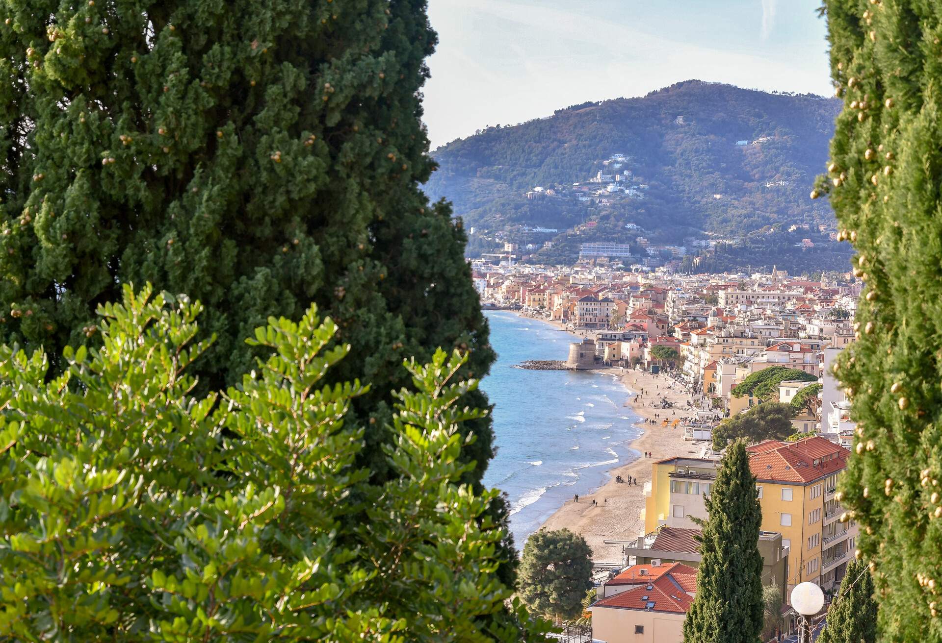 Panoramic view of the Ligurian coast with green trees in the foreground, Alassio, Liguria, Italy