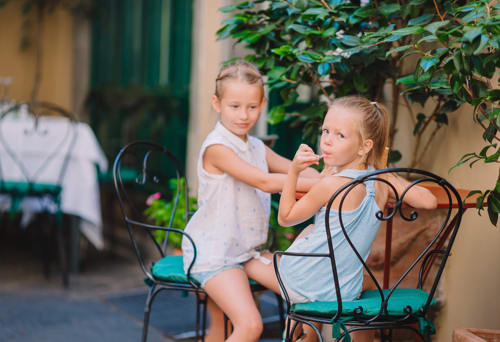 Adorable little girls eat ice-creamin outdoor cafe