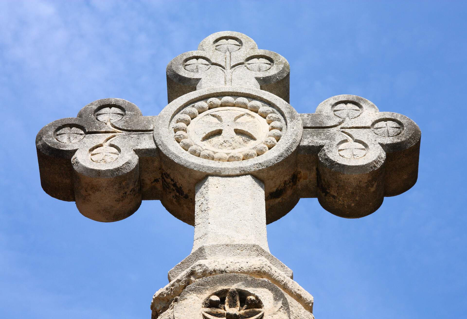 Cross made of stone with clover-shaped edges and a centre with circular carvings.