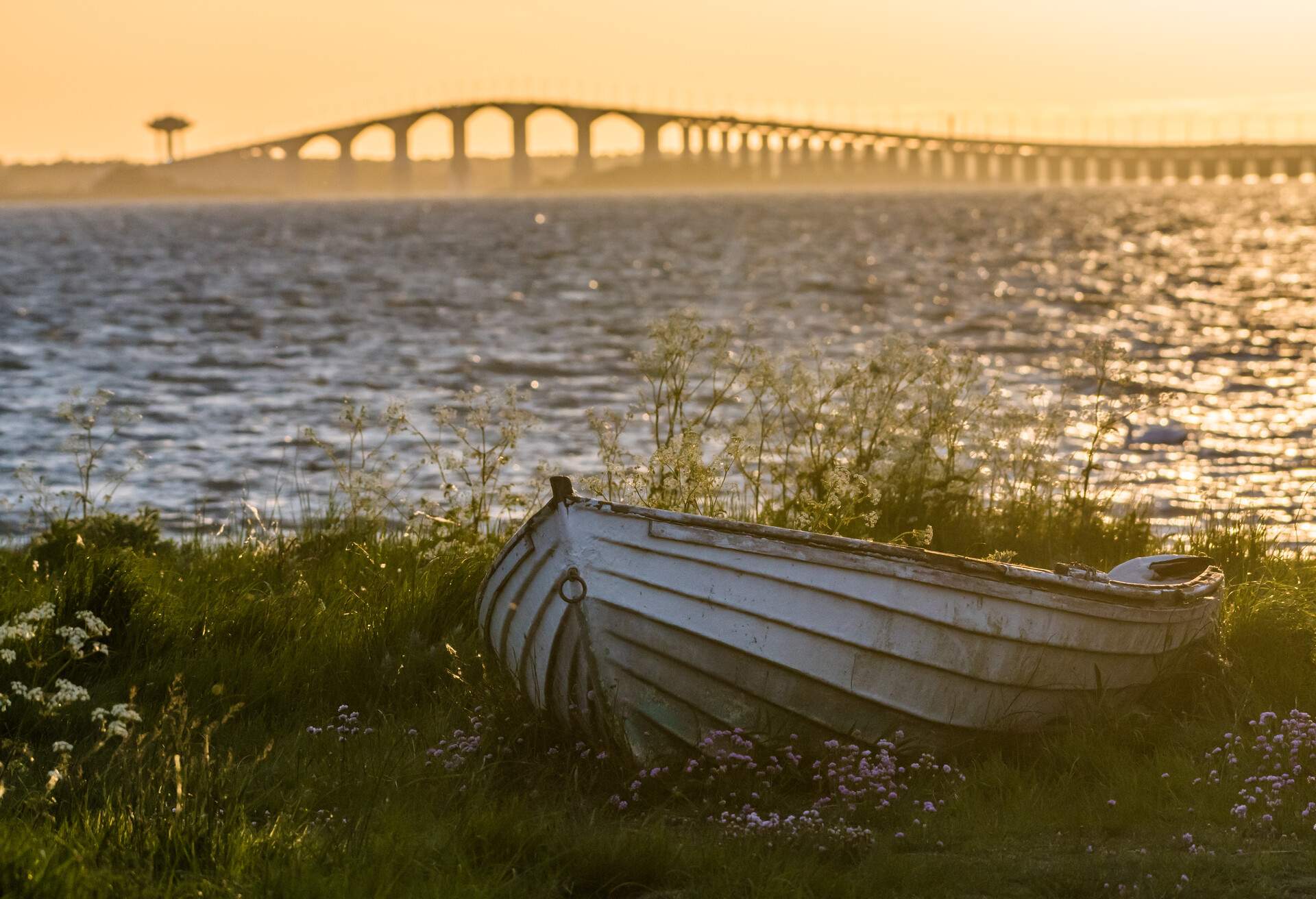 The swedish Oland Bridge with an old weathered rowing boat on land in the front