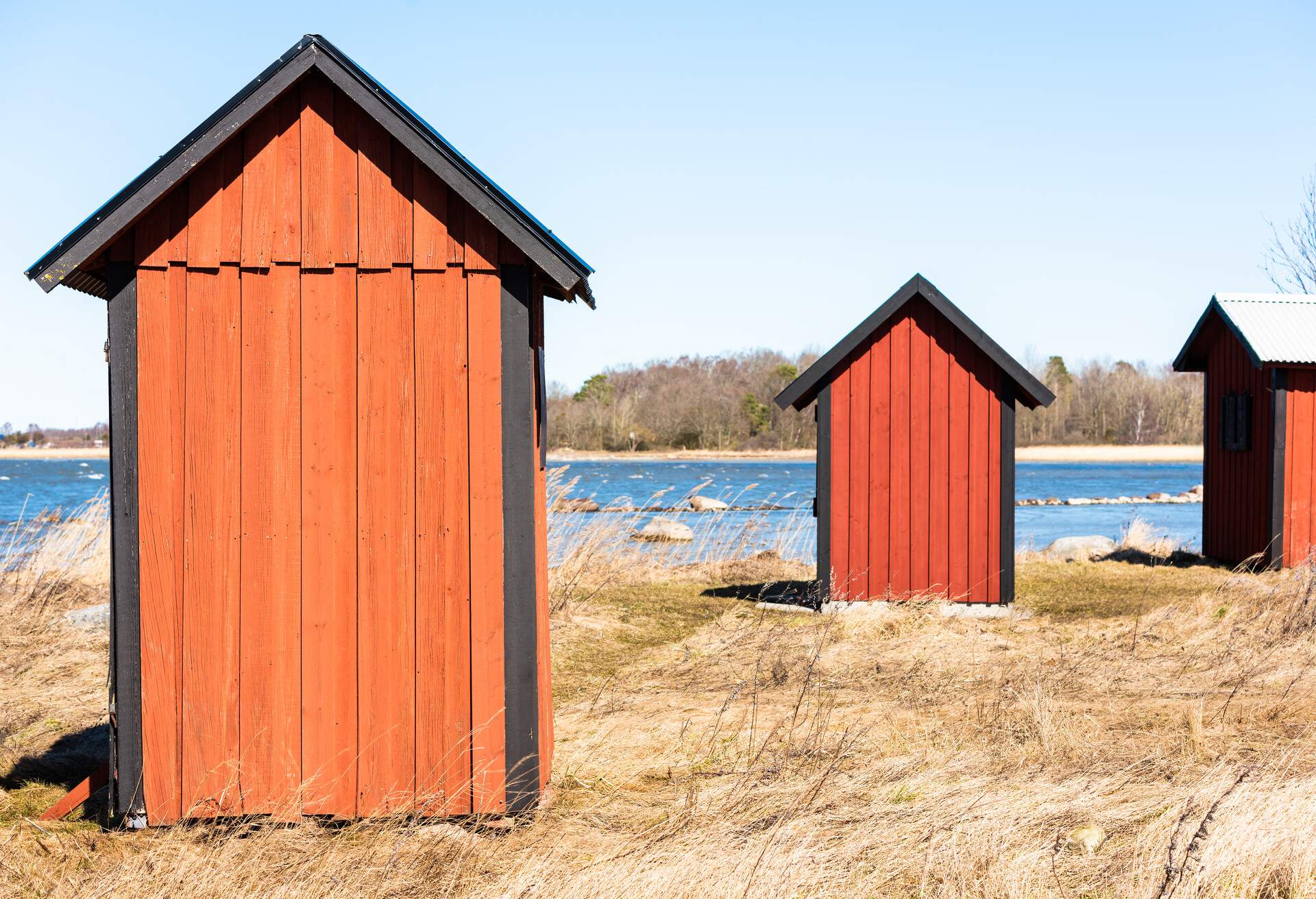 Small fishing sheds in coastal landscape on a sunny and windy day. Location Farjestaden, on the island of Oland, Sweden.