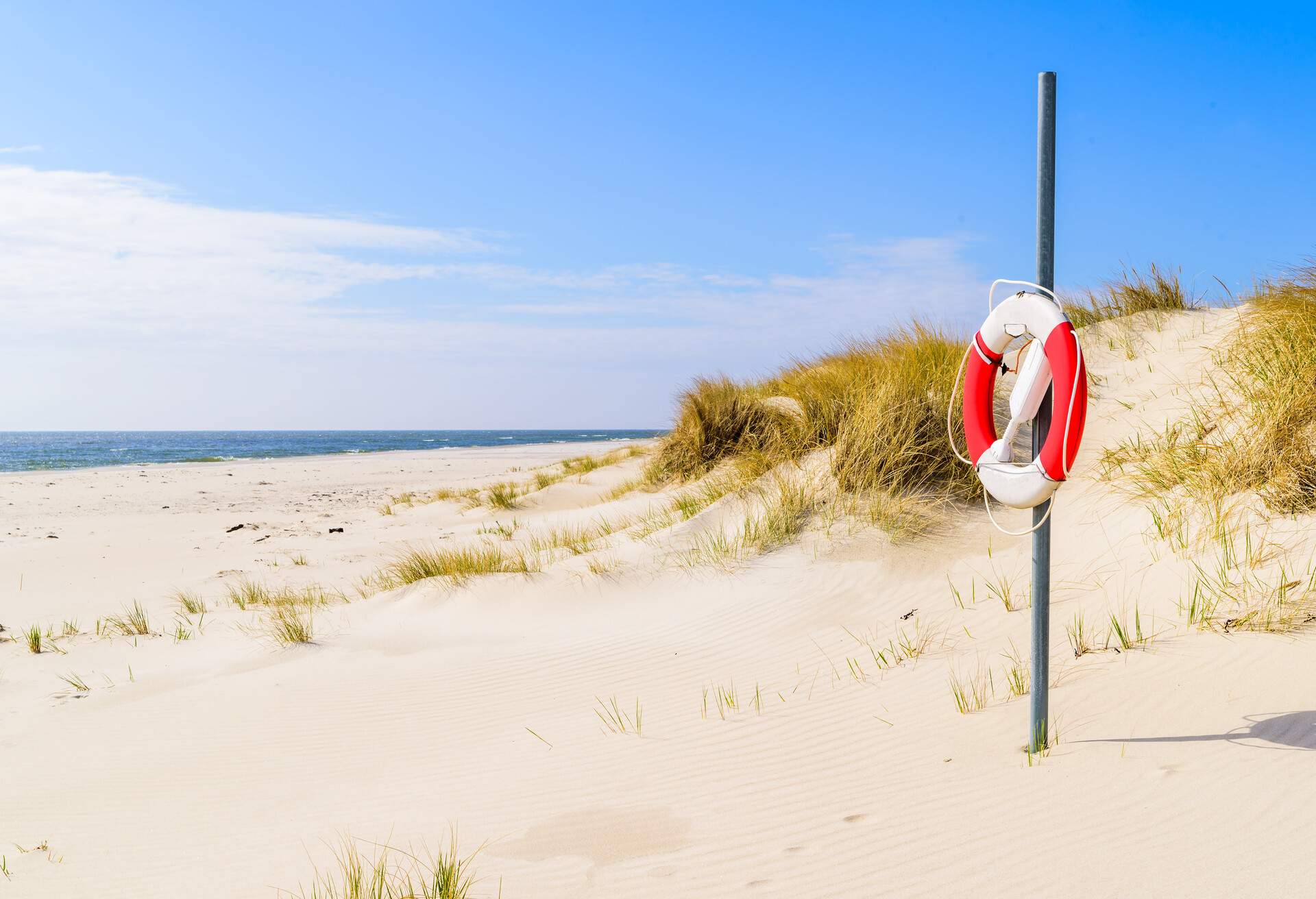 Malarhusen, Sweden - Lifebuoy on an empty sandy beach on a sunny day.