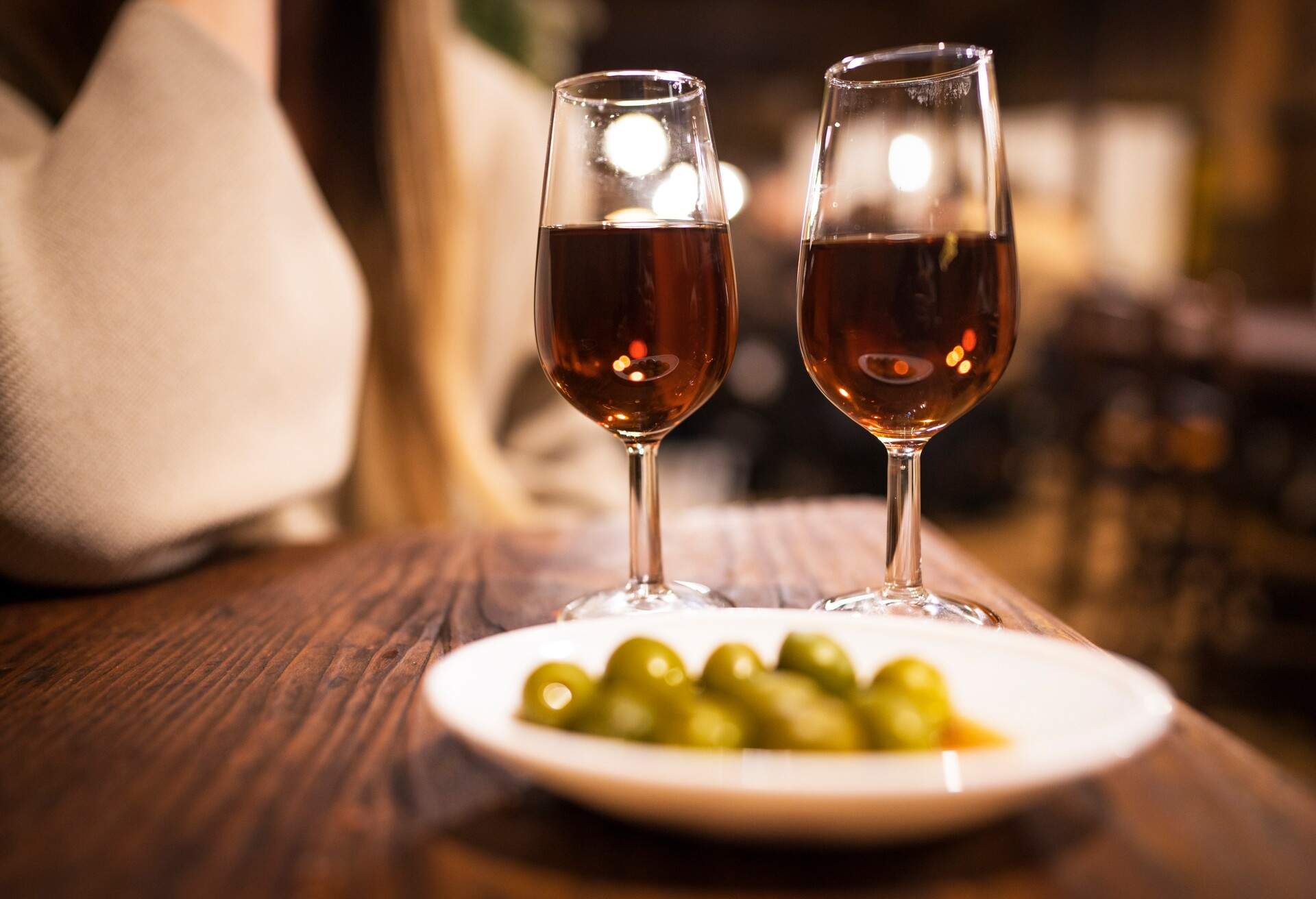An exquisite serving of vermouth accompanied by delectable olive tapas is presented for two at a rustic and classic wine bar.