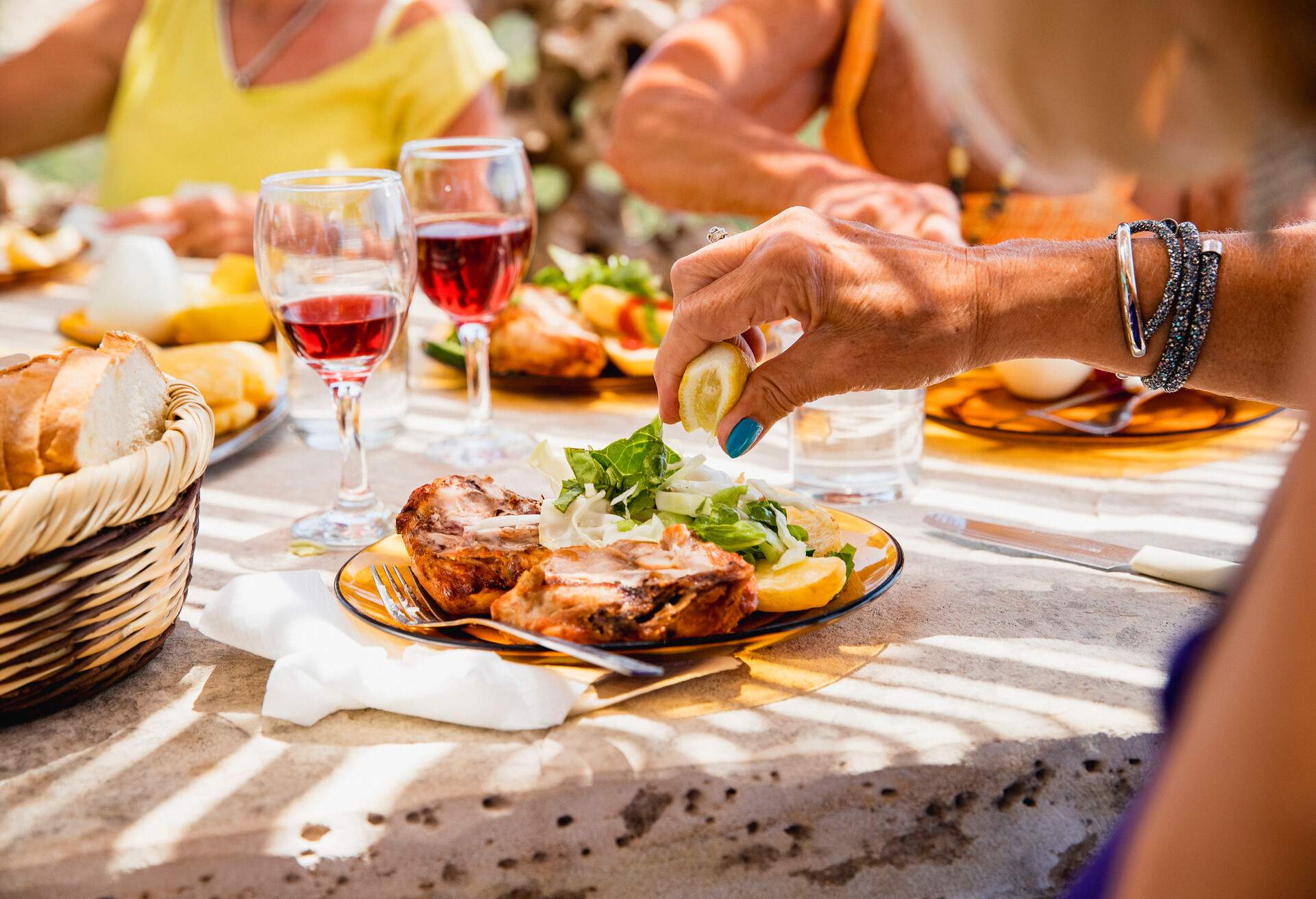 Lady enjoying her food served with half a plate of meat and the other half salad. She is sat at the table with her friends in the restaurant on their holiday.