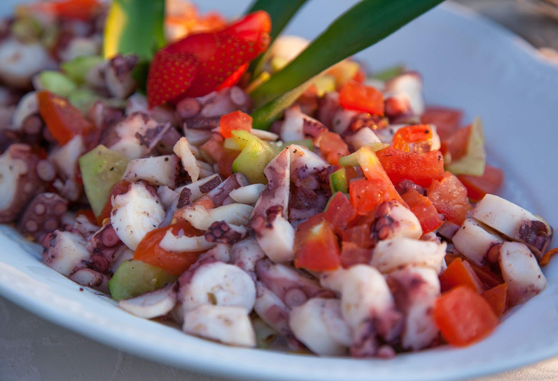 Composition for aperitifs and buffet service with octopus, potatoes and tomatoes in vinagrette with strawberries on display. Production in Tuscany, Italy