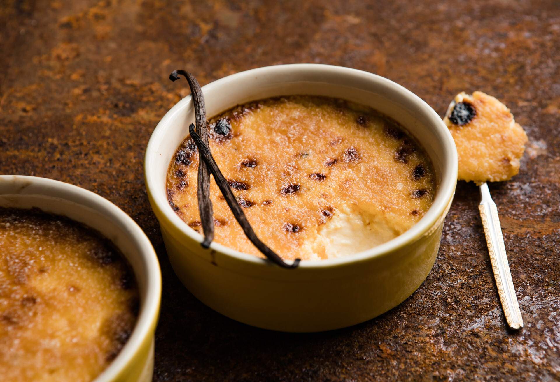 A tempting bowl of Spanish crema catalana presents a luxurious, velvety custard base beneath a glistening, cracked layer of caramelised sugar.