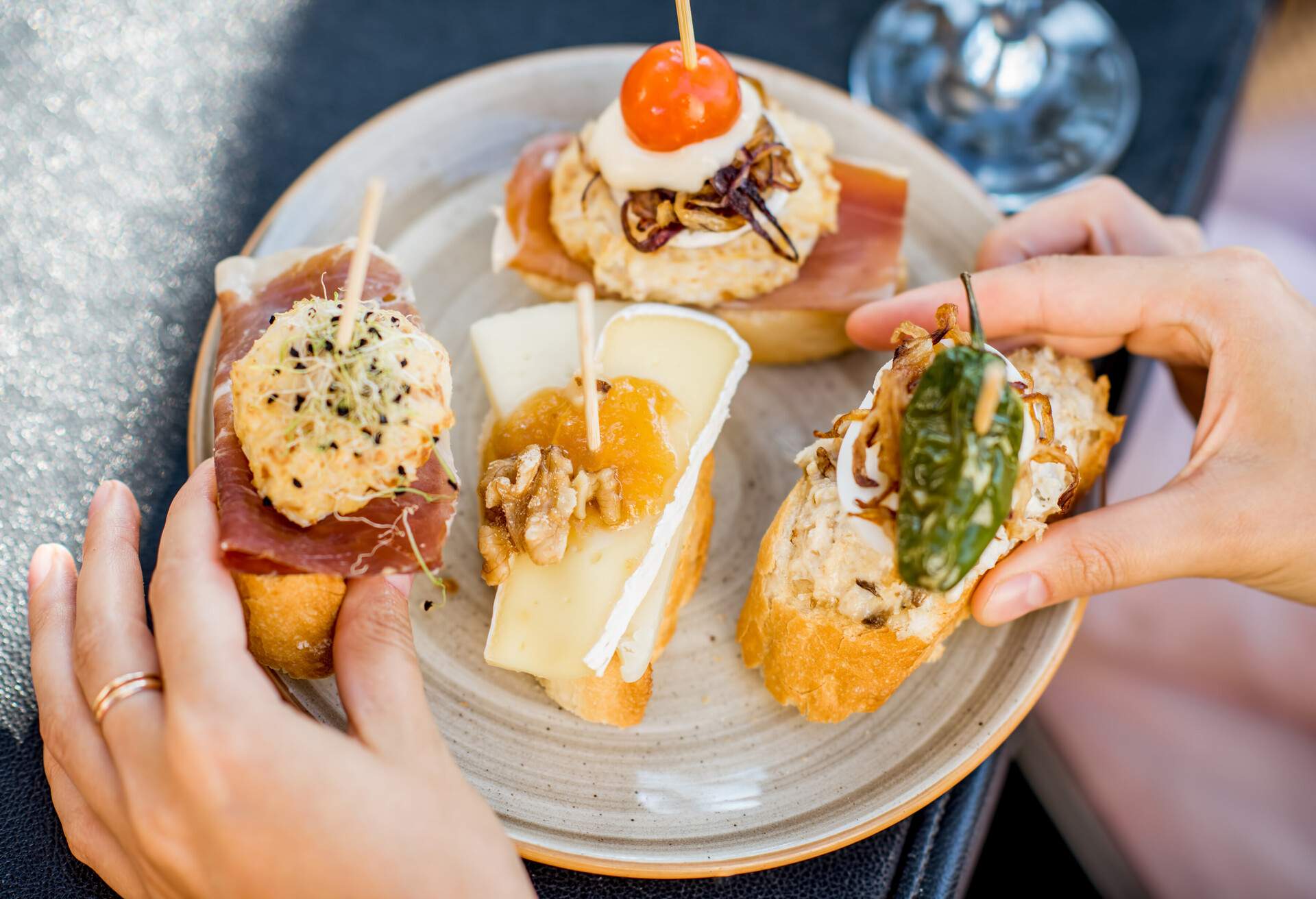 A woman assembling a variety of open-faced sandwiches on a plate.