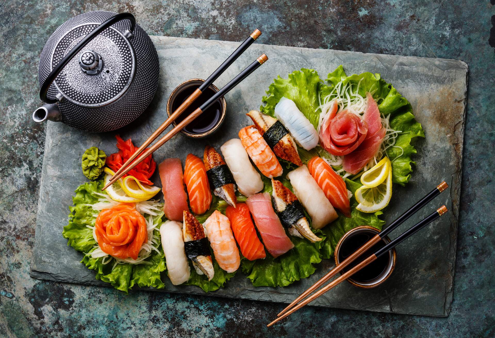 Sushi Set nigiri and sashimi with tea served on gray stone slate on metal background