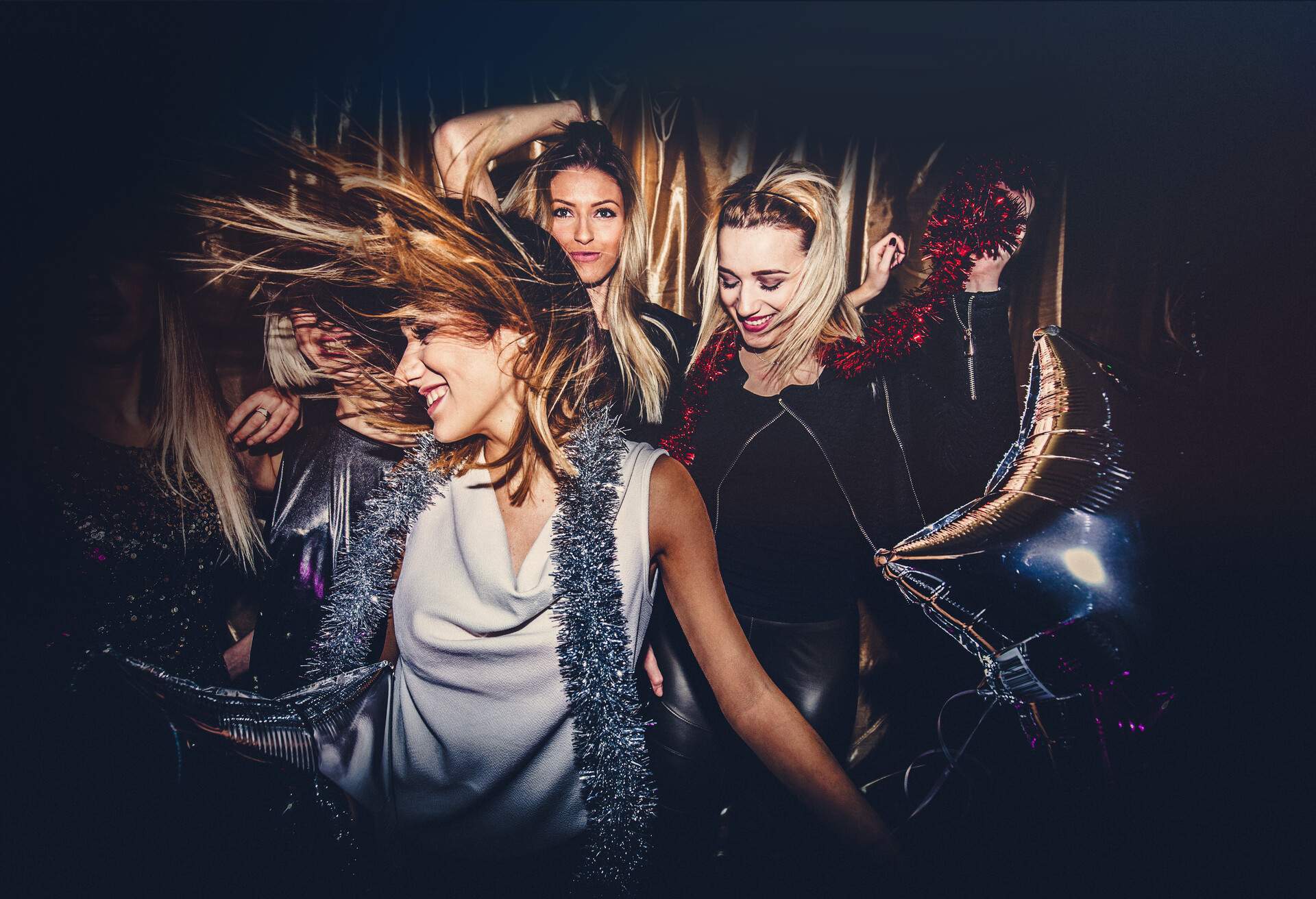 A circle of female friends enjoying the night dancing happily in a nightclub.