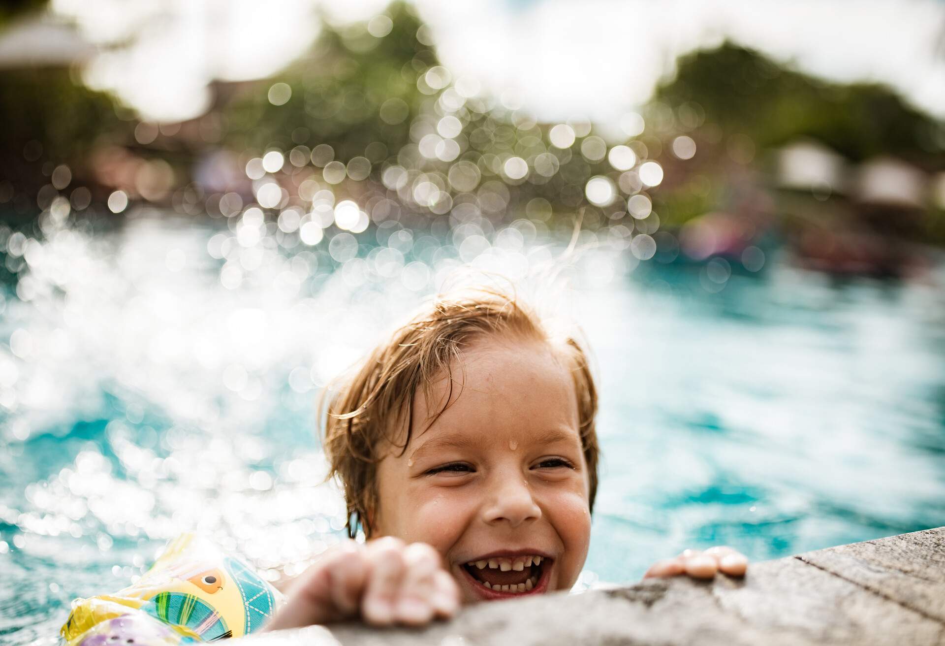 Portrait cute small boy splashing in the pool