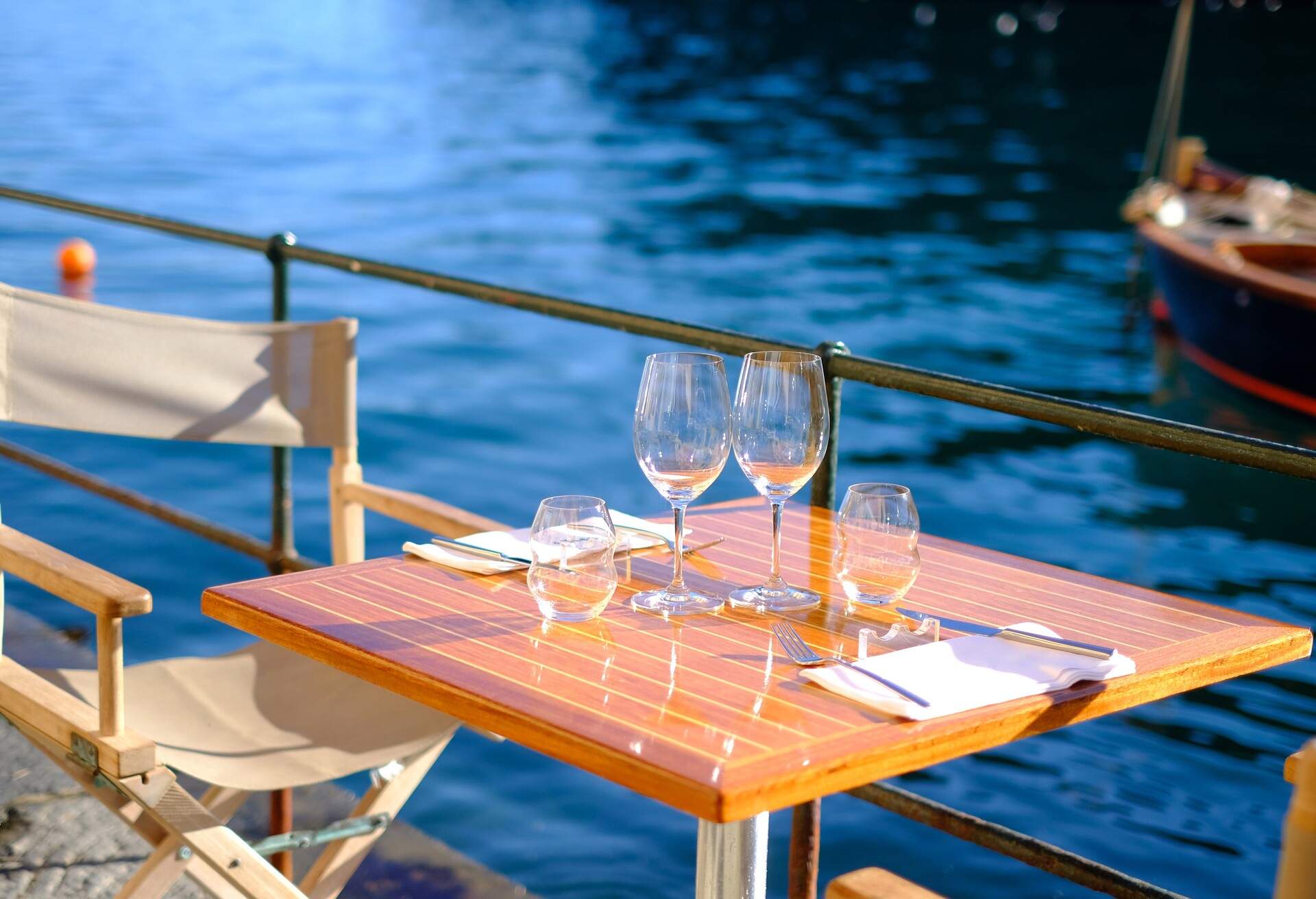 Outdoorly set wooden restaurant table on the quay of the marina of Riomaggiore overlooking the sea a rowing boat
