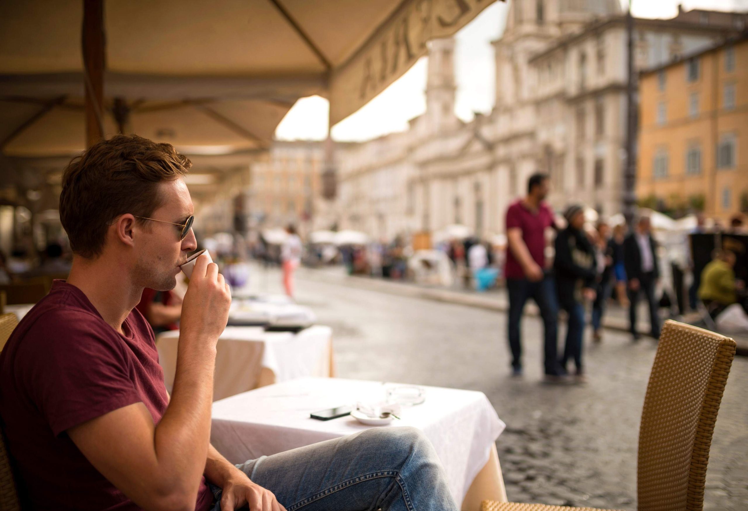A man sits at an outdoor restaurant as he enjoys his espresso.