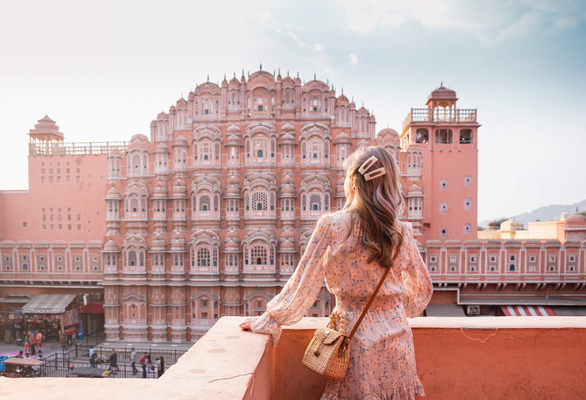 A female tourist stands on the balcony overlooking the picturesque pink-coloured sandstone palace.